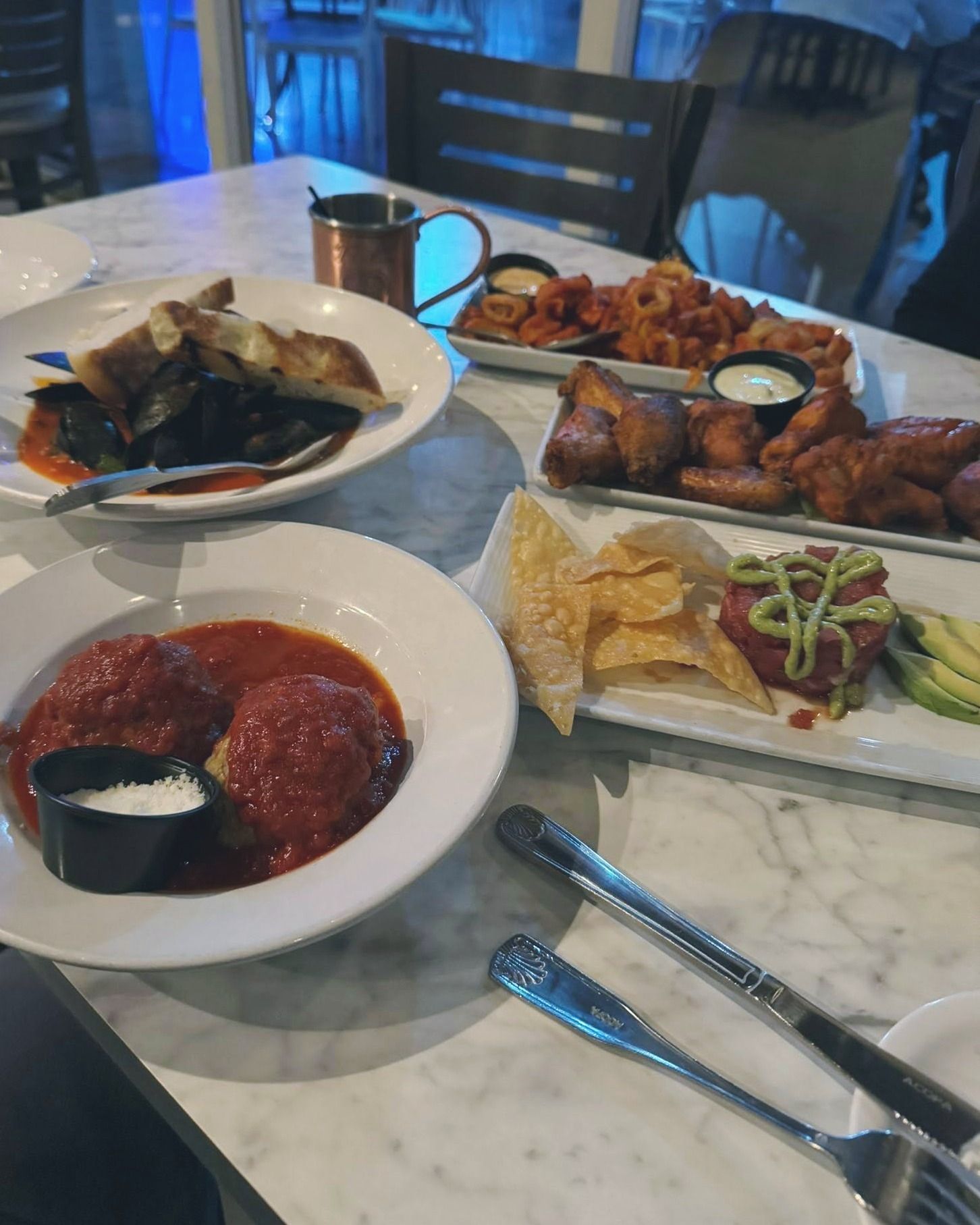 Table with various dishes. Meatballs, fried food, and seafood.