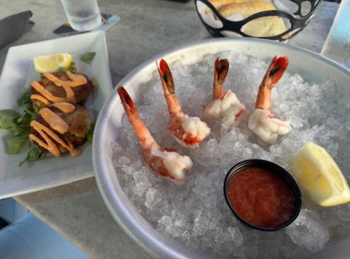 Shrimp cocktail with sauce and lemon wedge, served over ice. Crab cakes with sauce.
