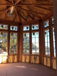 Interior of a wooden gazebo with multiple windows, insulation, and sunlight