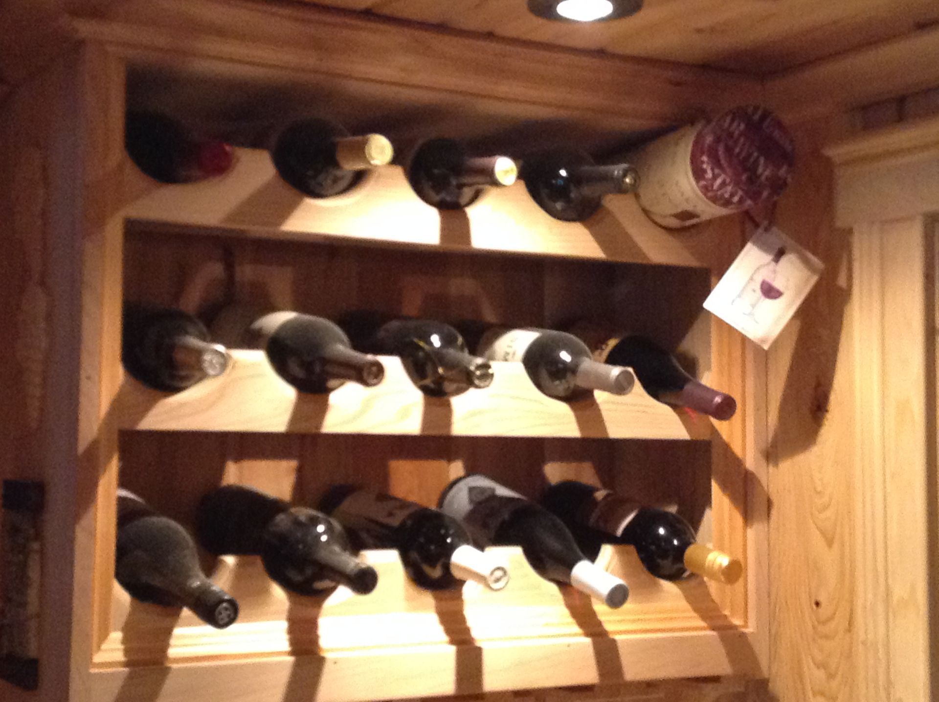 Wine bottles stored horizontally in a wooden rack within a wooden cabinet