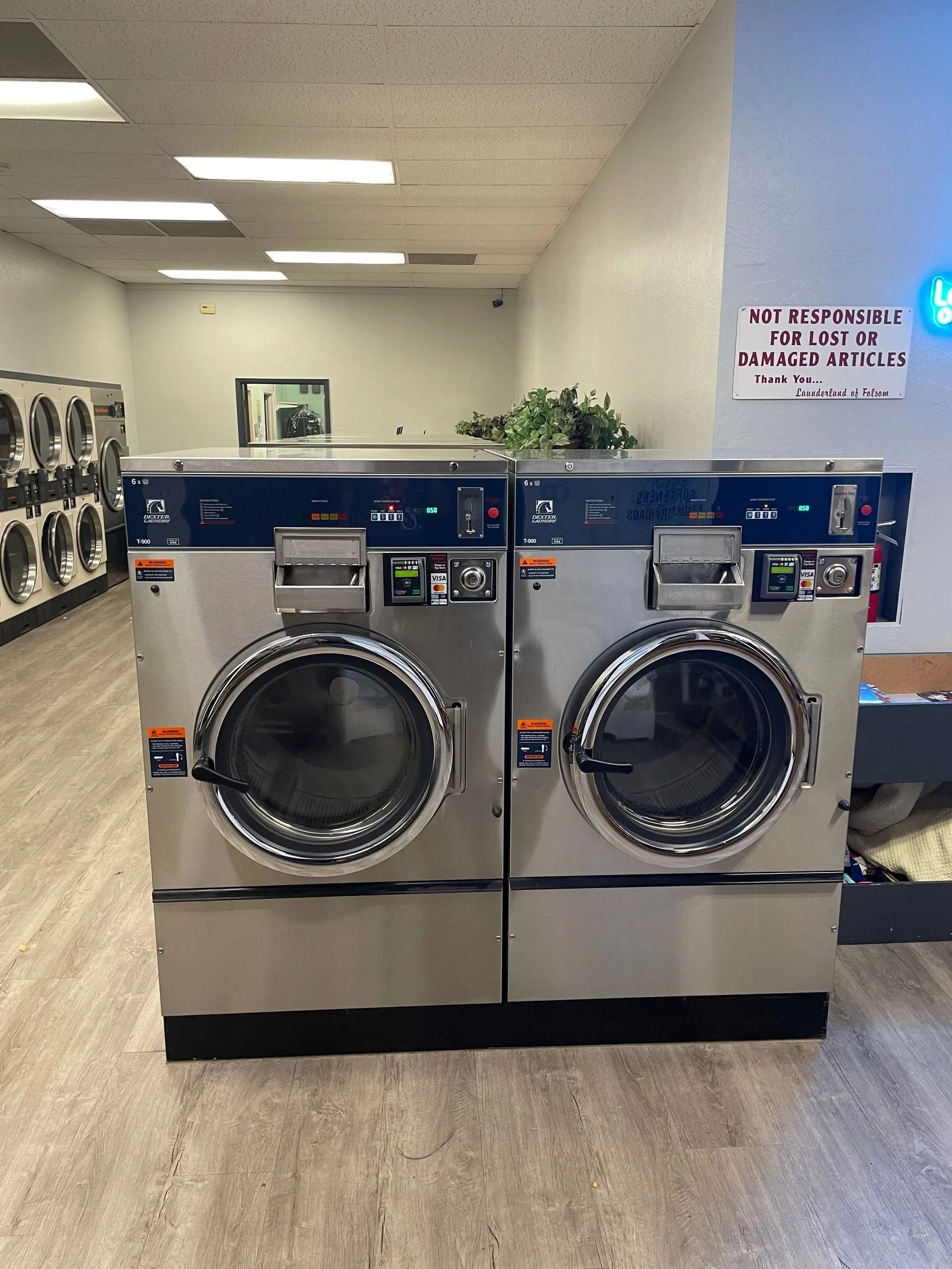 Two large stainless steel washing machines in a laundromat.