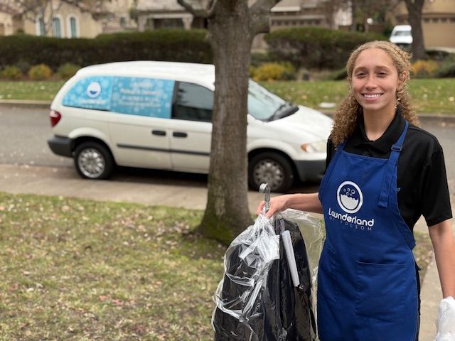 Woman holding dry cleaning bag, standing in front of a van with 