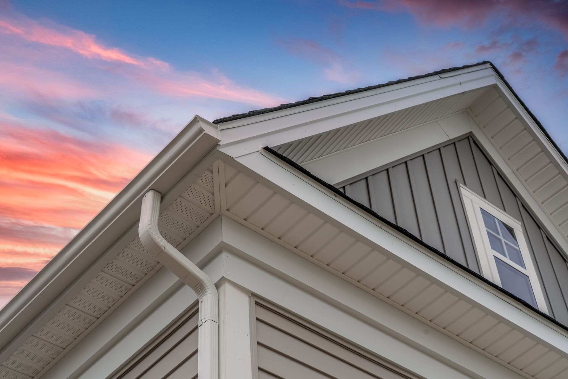 A close up of the roof of a house with a sunset in the background.