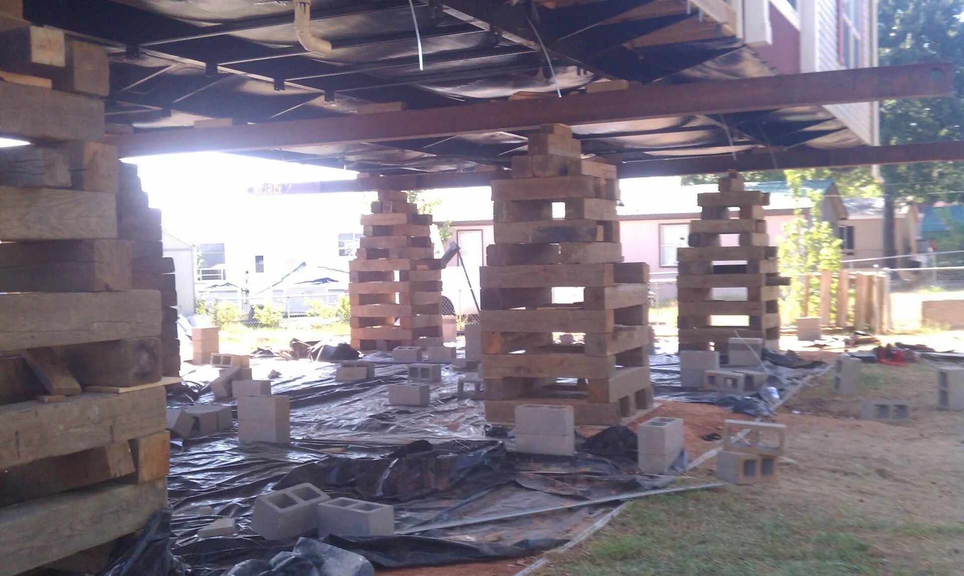 Charred wooden deck supports after a fire, with debris scattered beneath the structure.