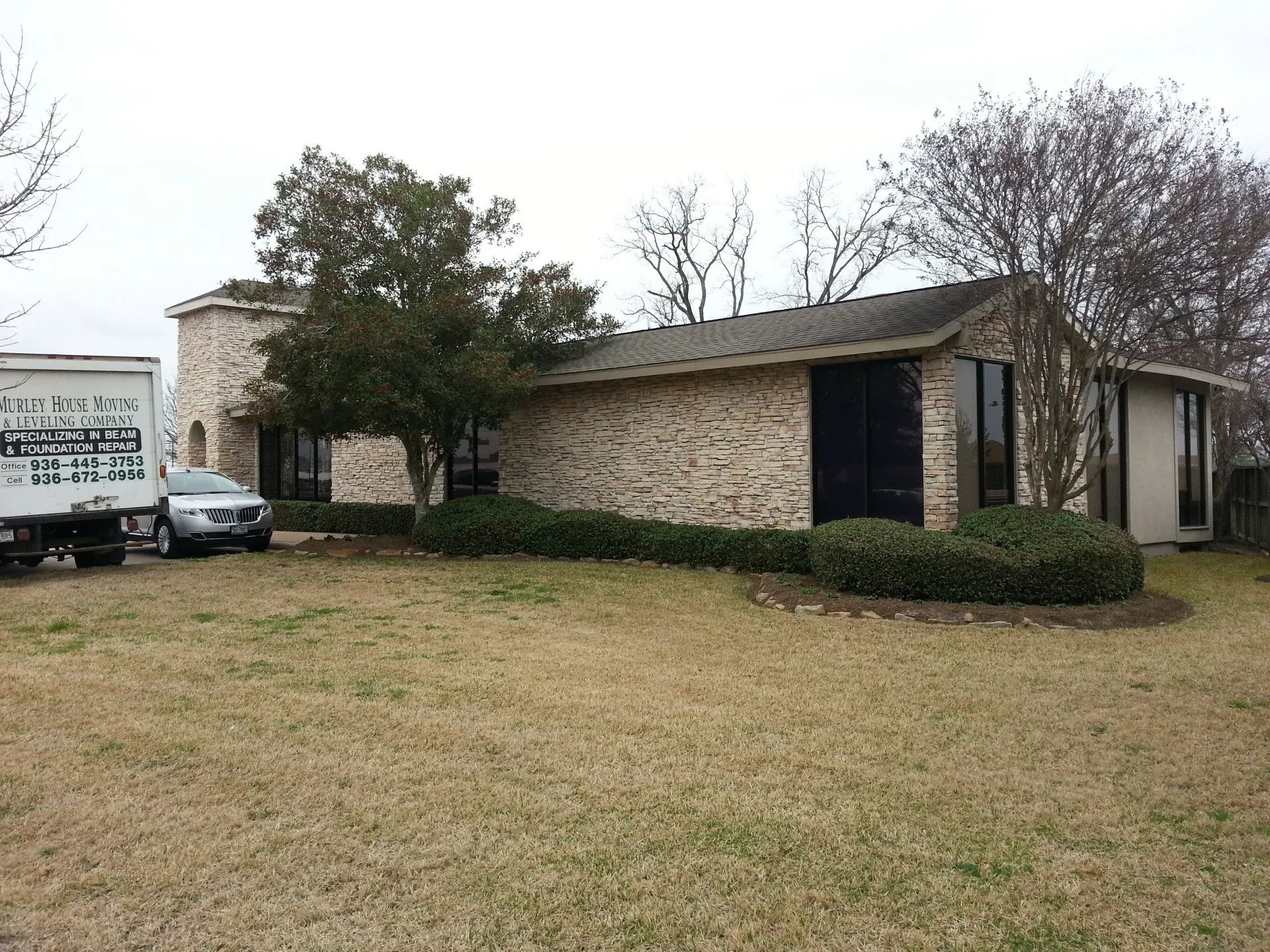 Single-story brick house with a front lawn and a parked vehicle on the left