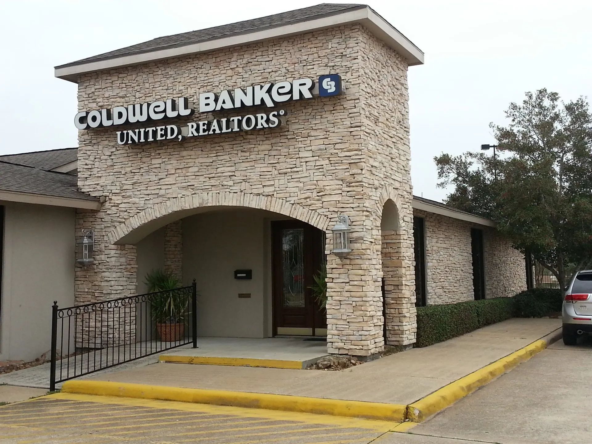 Coldwell Banker United Realtors office entrance with stone facade and yellow curb