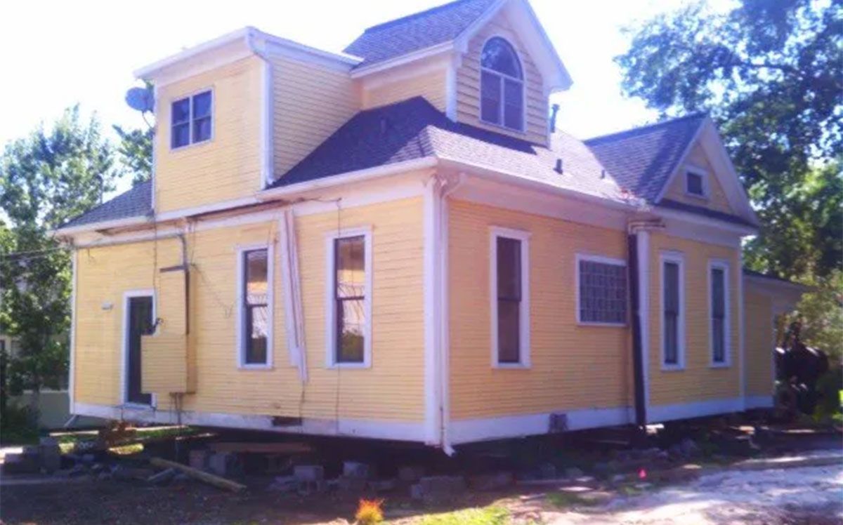 Yellow two-story house with white trim and a front porch, seen from the side.