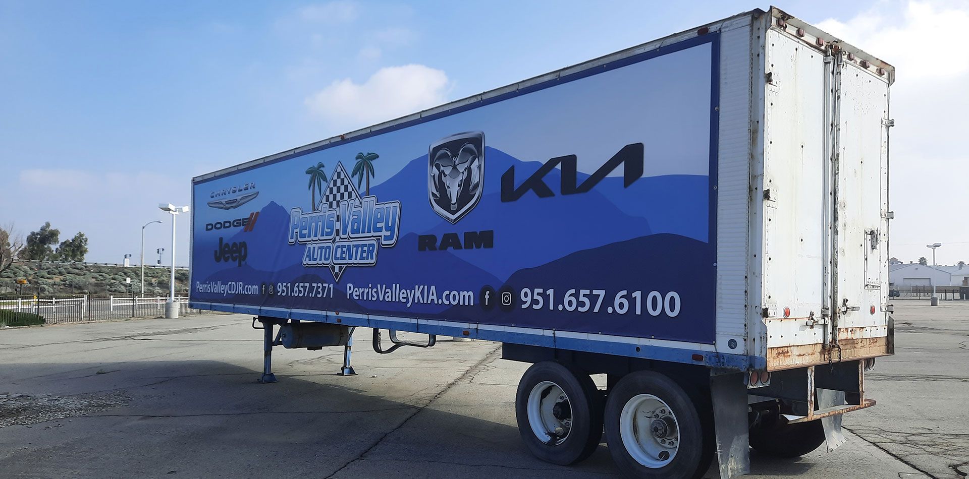 Blue and white KIA box truck parked in a lot on a sunny day