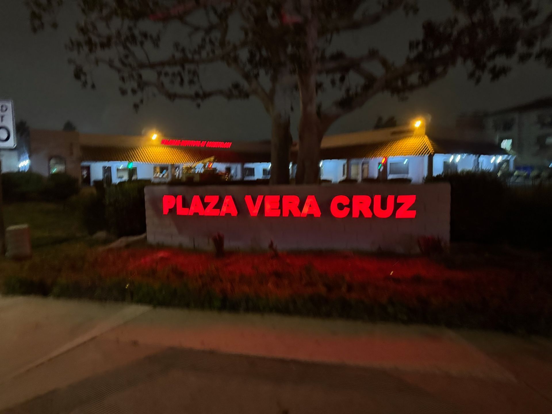 Night view of Plaza Vera Cruz sign glowing red in front of a landscaped plaza
