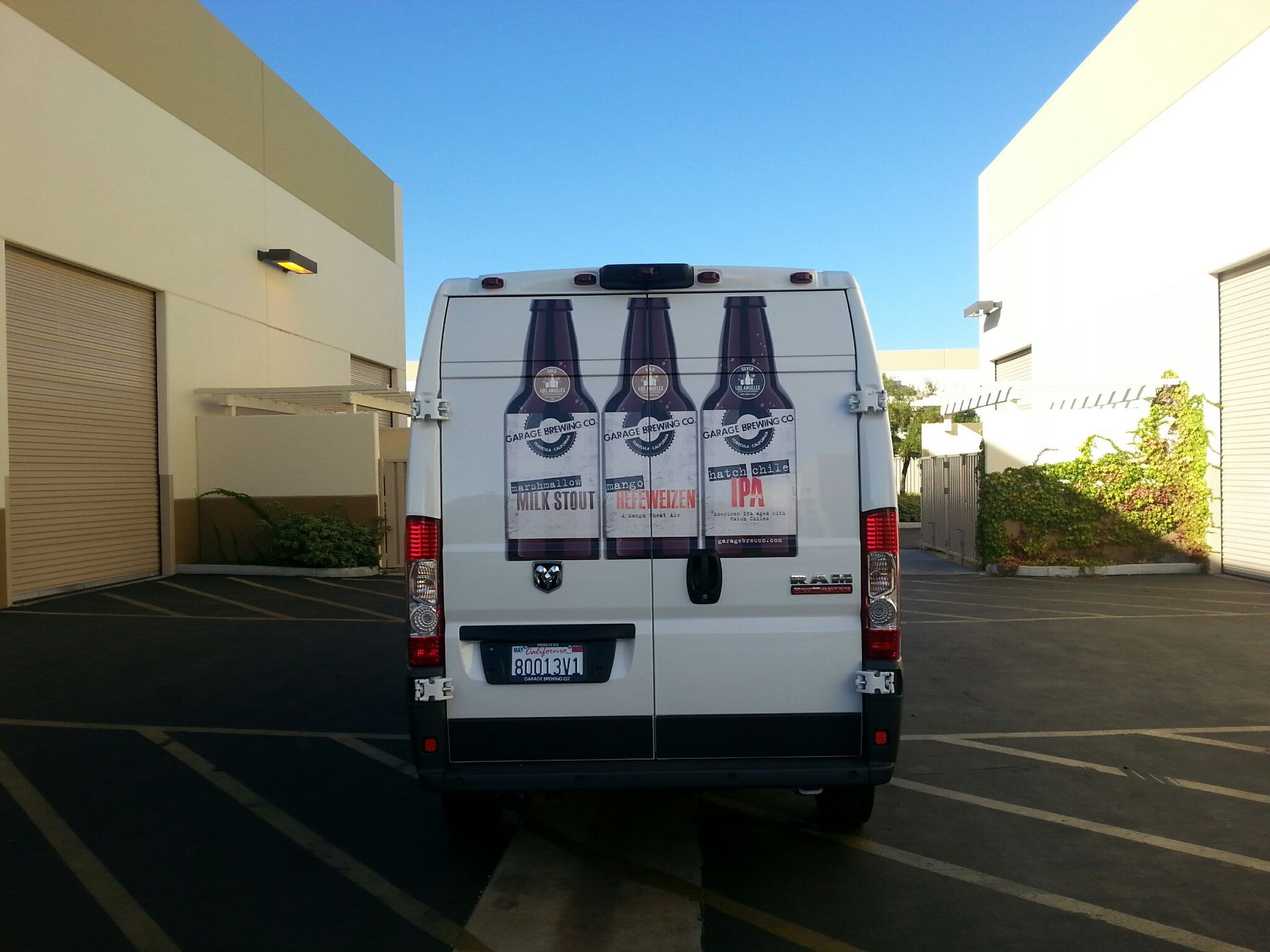 White van parked in a lot, viewed from the rear, with bottle graphics on the back doors.