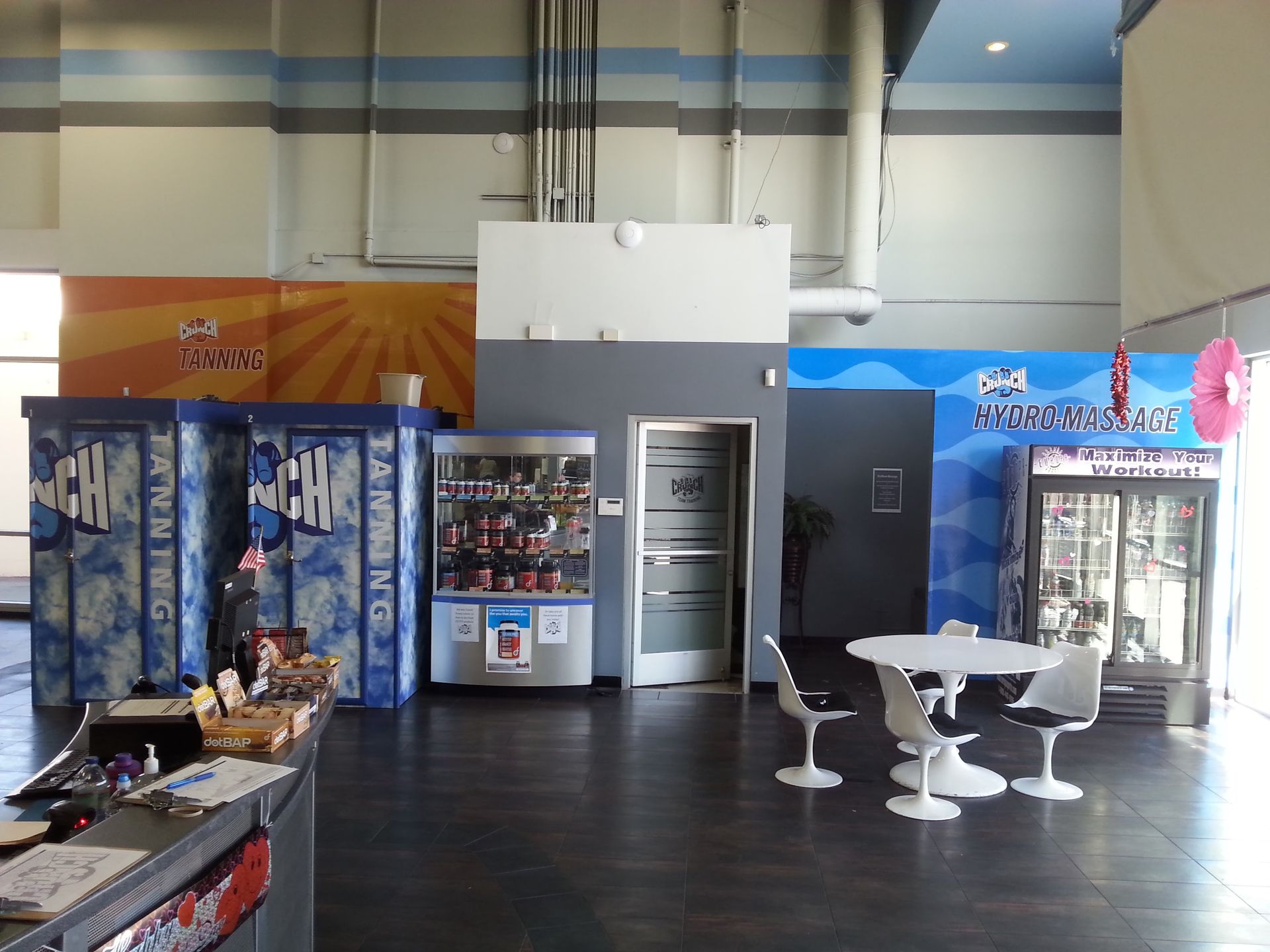 Small store seating area with vending machines, a refrigerator, and tables against blue and orange walls