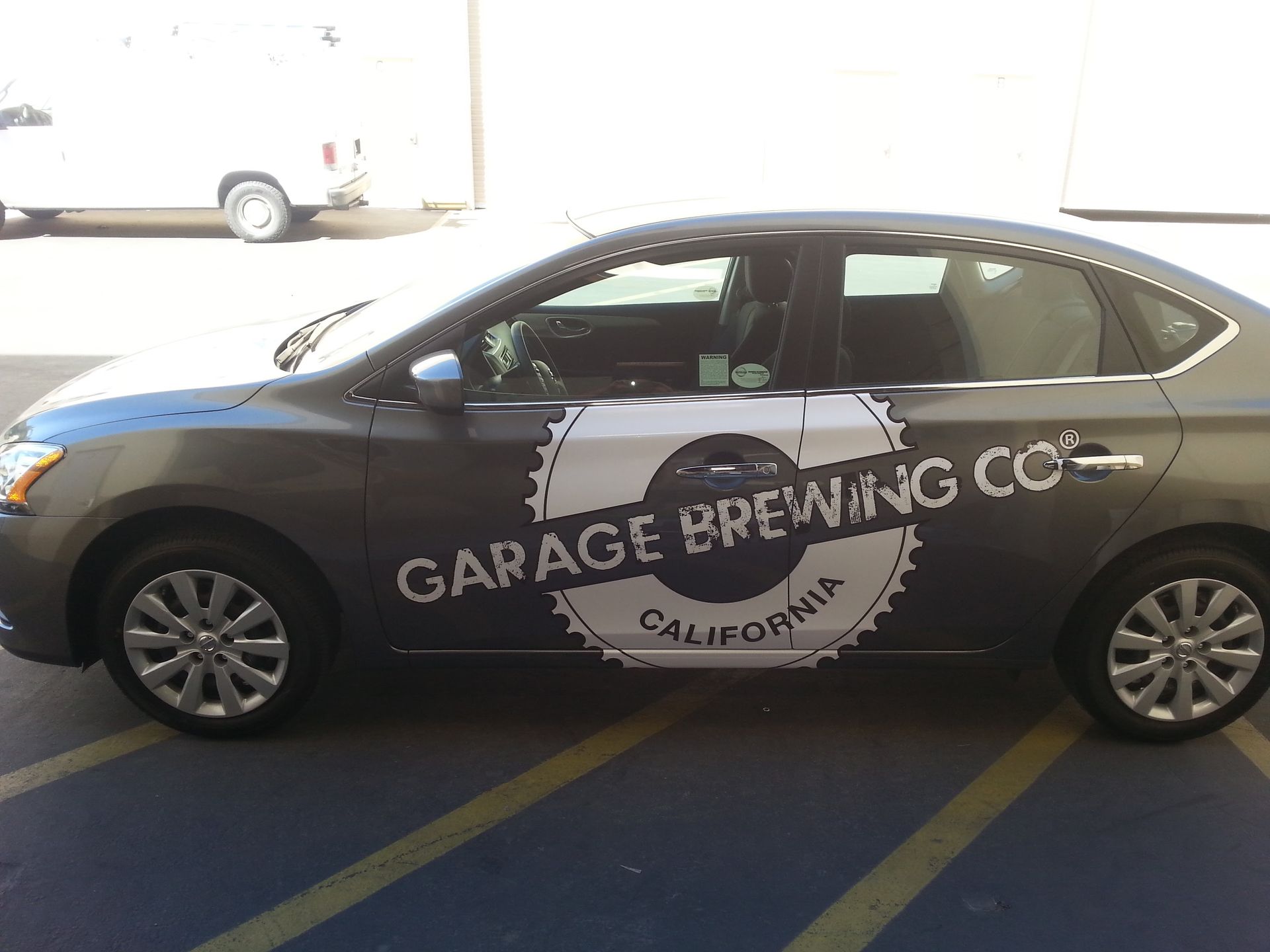 Black sedan with Garage Brewing Co. logo parked in a striped lot