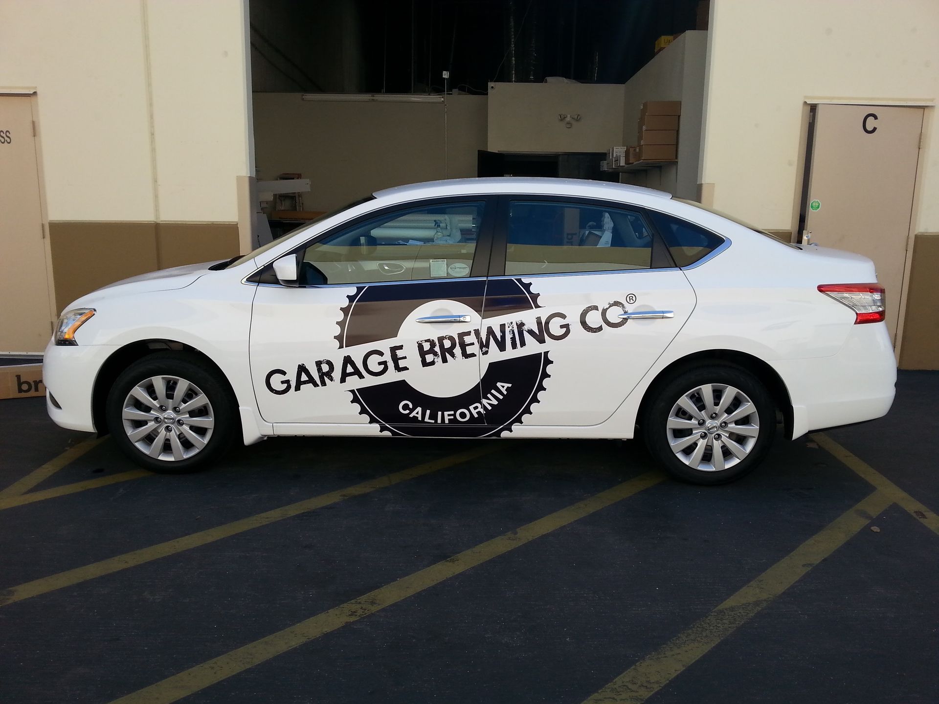 White sedan with Garage Dooring Co. logo parked outside a garage