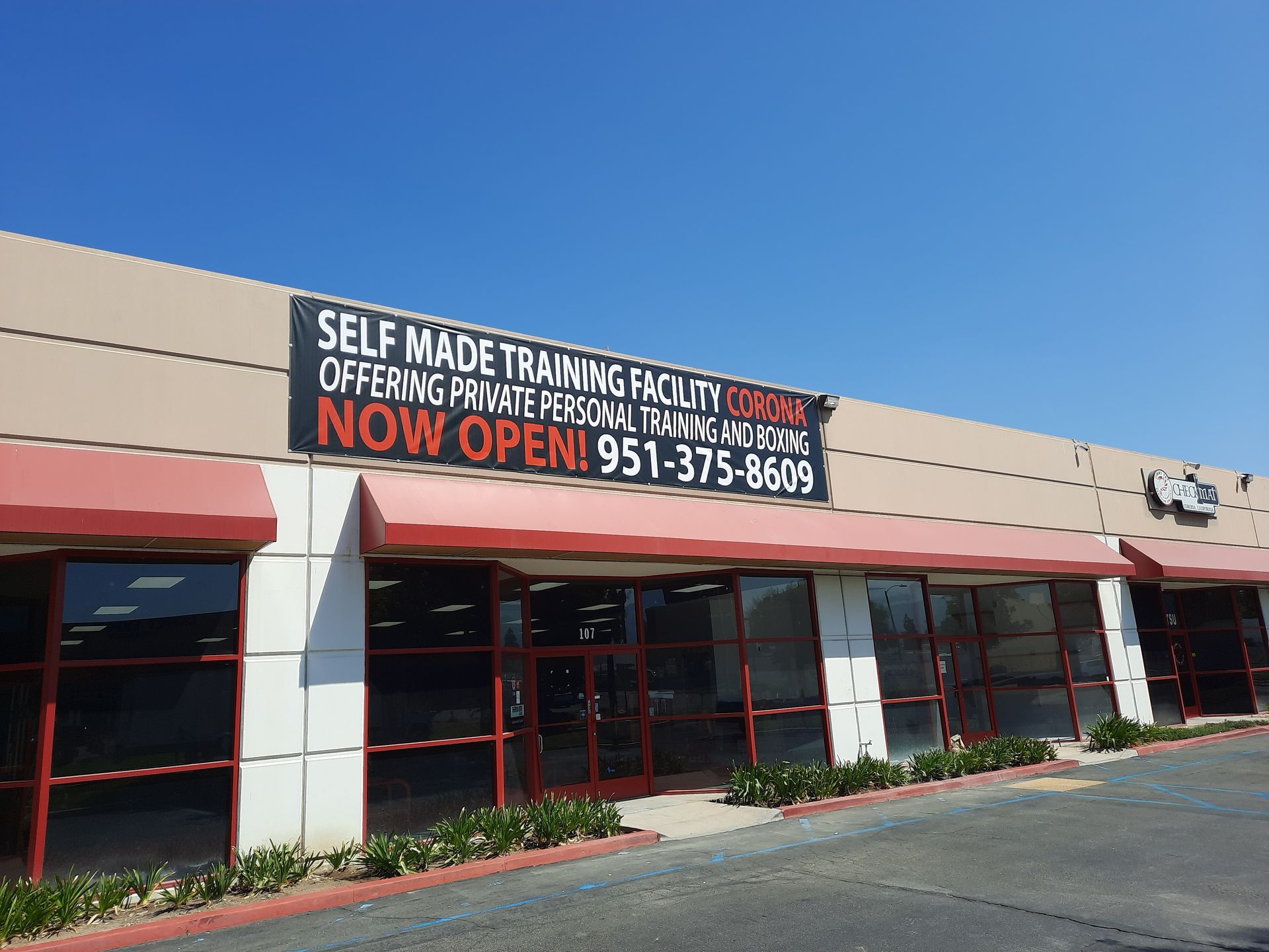 Storefront with a large “Self Made Training Facility” sign and red awnings on a sunny day