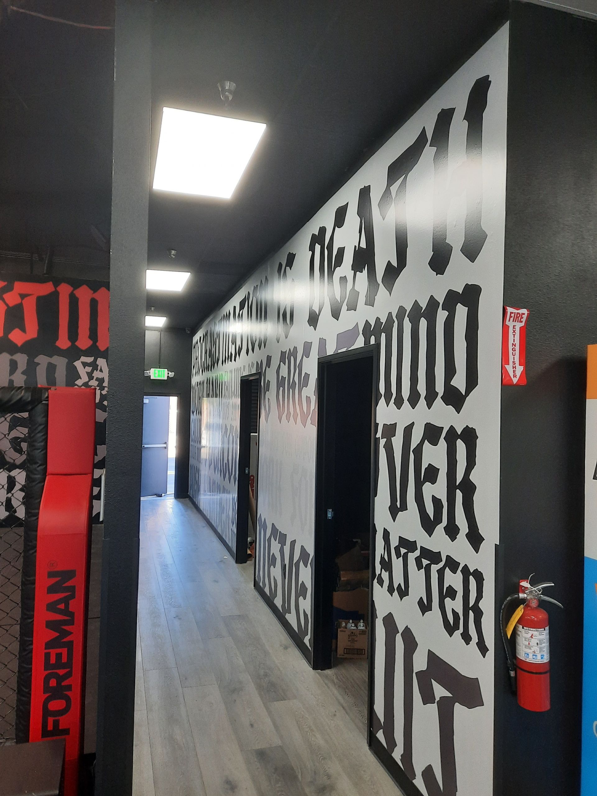 Narrow hallway with black-and-white graffiti murals, red accents, and bright ceiling lights.
