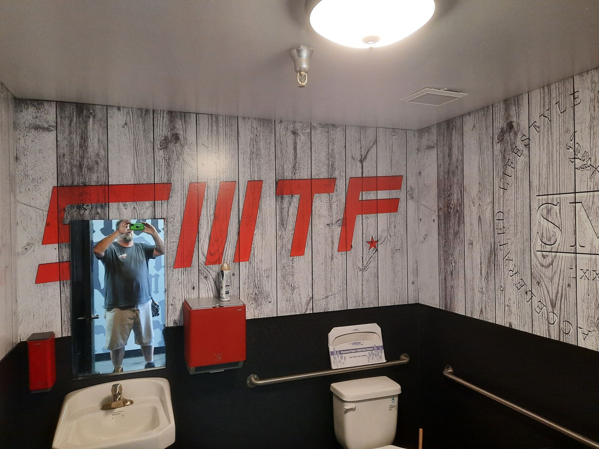 Bathroom with red and white logo mural, toilet, sink, and towel on the wall