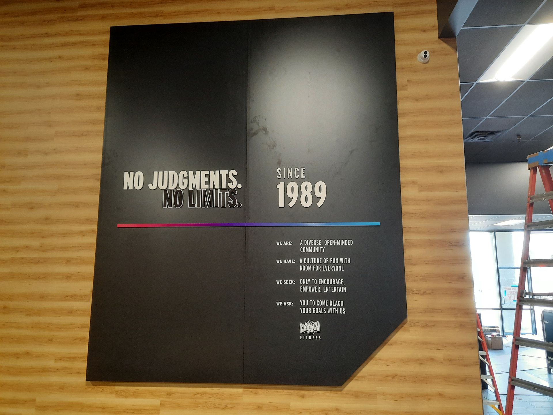 Black poster on wood wall reading “No Judgments, No Limits” with “1989” and small event text.