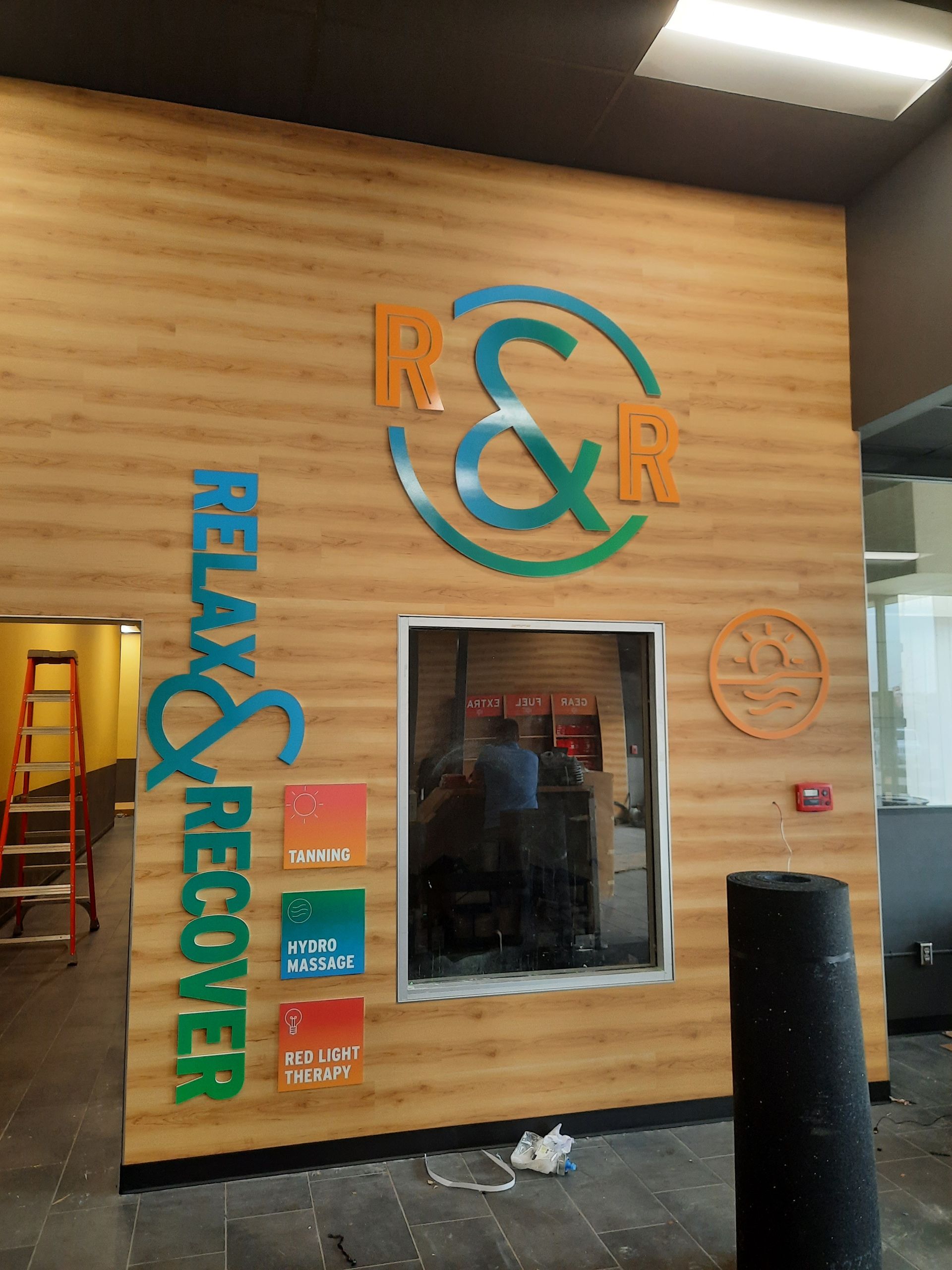 Wood-paneled storefront wall with colorful “Relax & Recover” signage and a window
