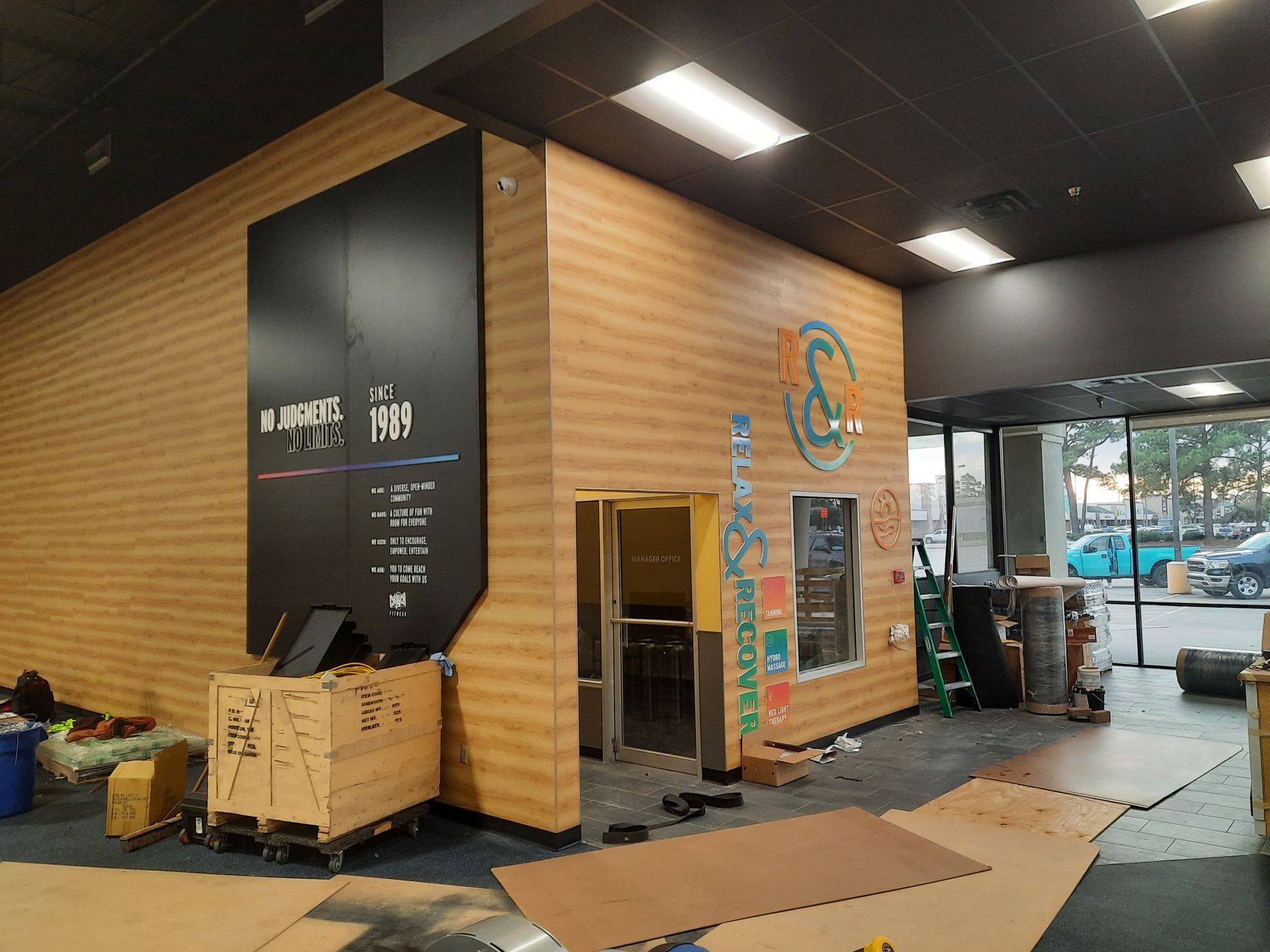 Indoor lobby with wood-paneled walls, black ceiling, and cardboard boxes near a front desk area.