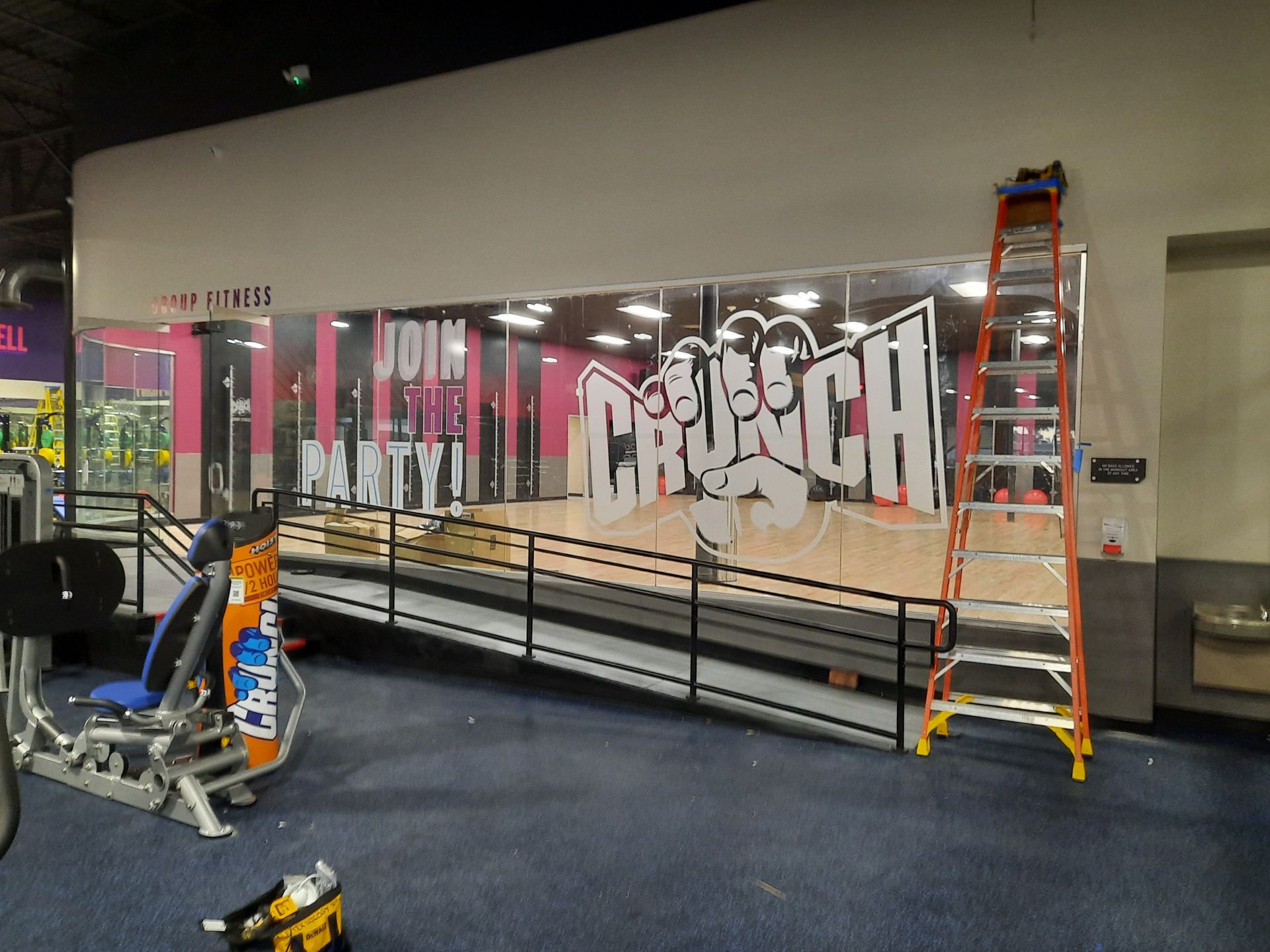 Indoor gym wall mural with graffiti-style lettering, a ladder, and sports equipment on the floor