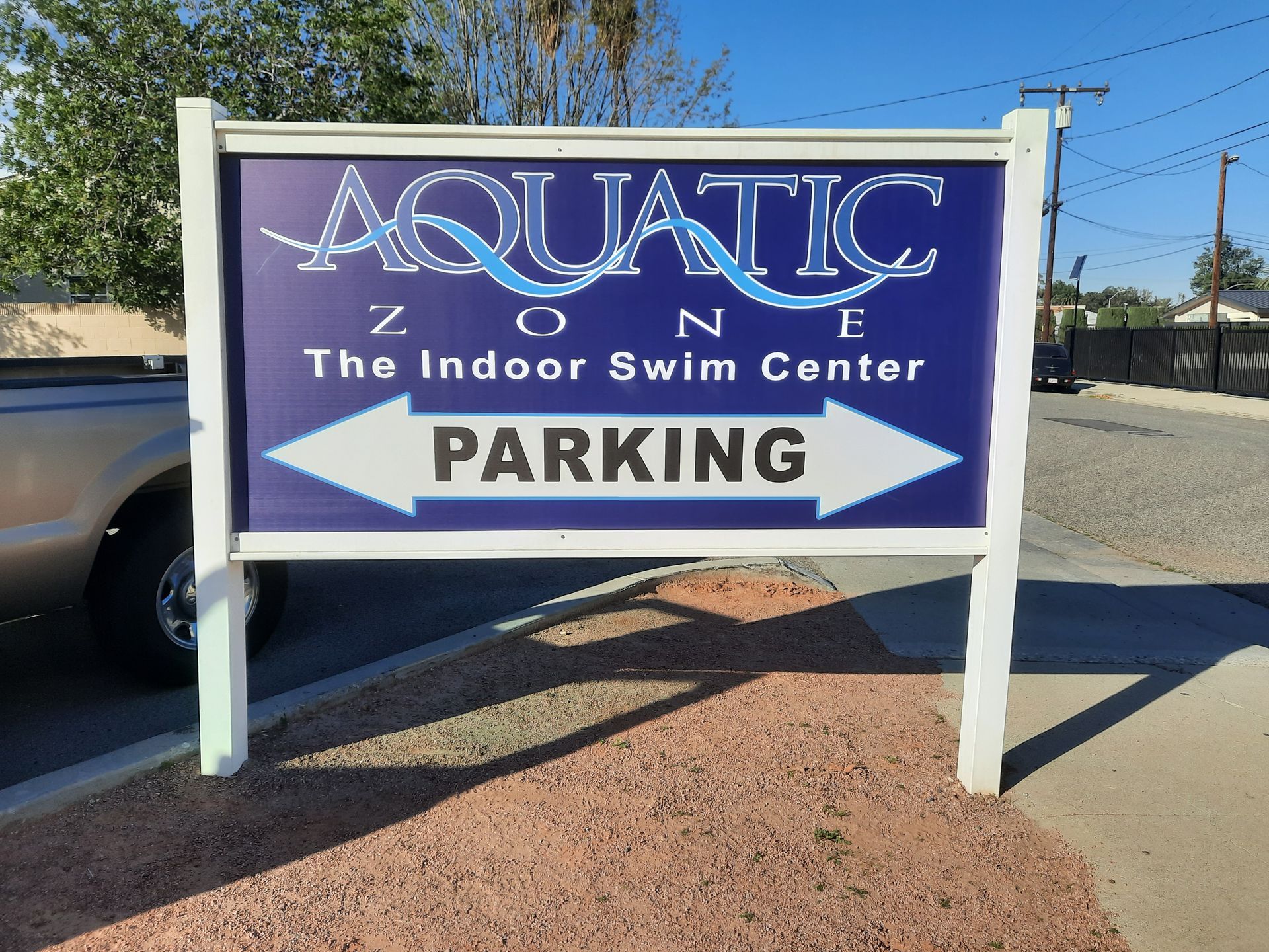 Aquatic The Indoor Swim Center parking sign with white arrow on blue background outdoors