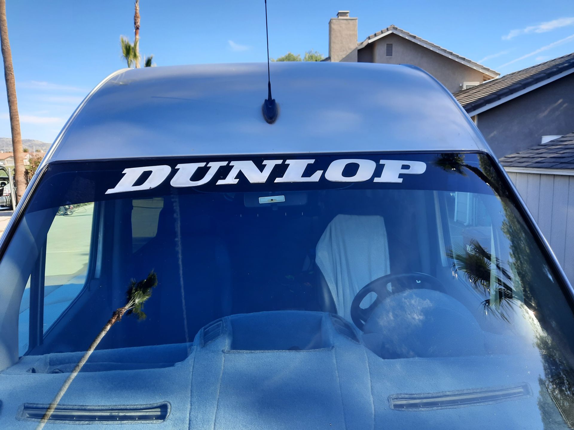 Blue van windshield with large white “DUNLOP” banner decal