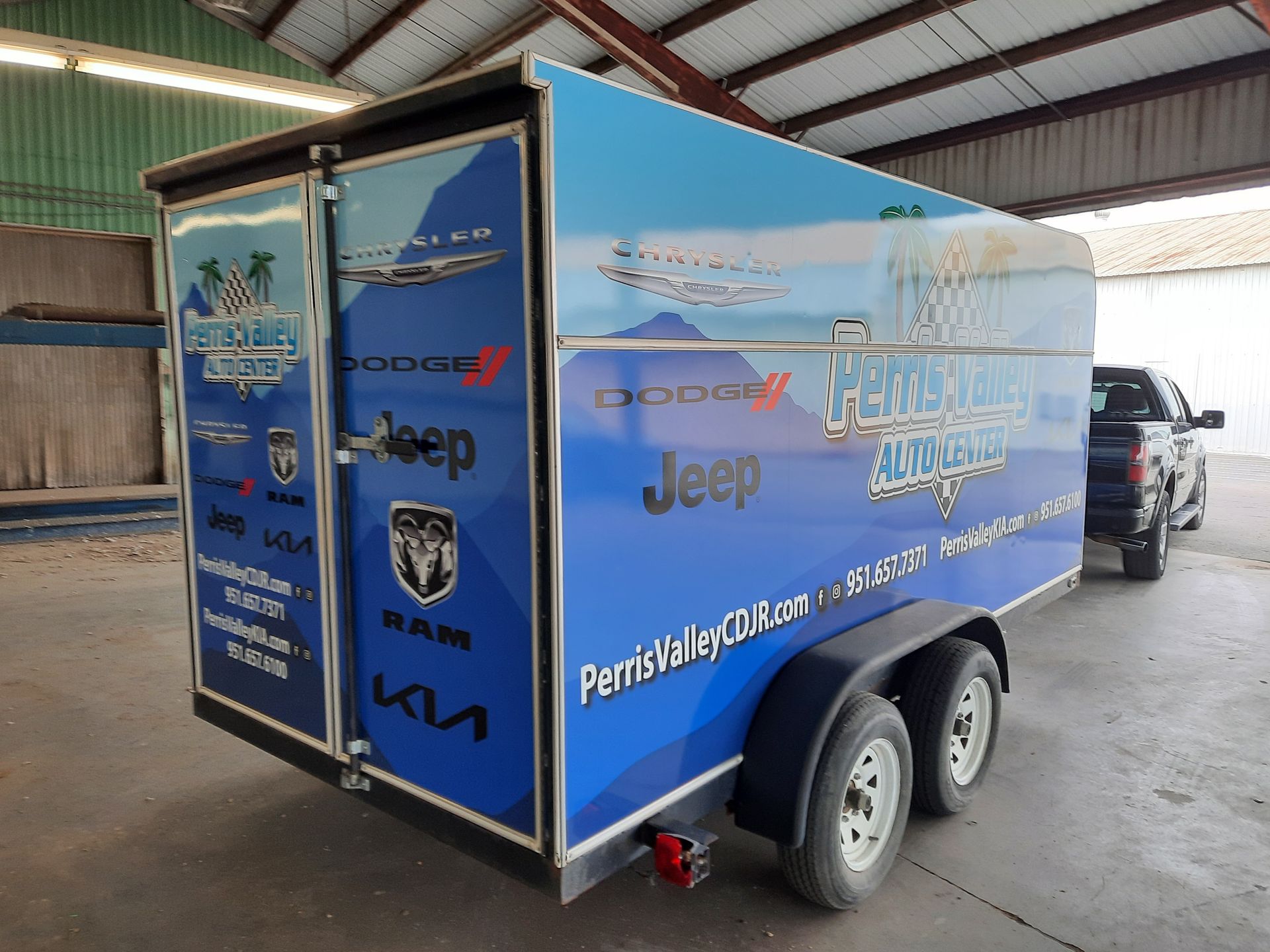 Blue Jeep-branded box trailer parked in an indoor garage, with logos and a rear door visible.