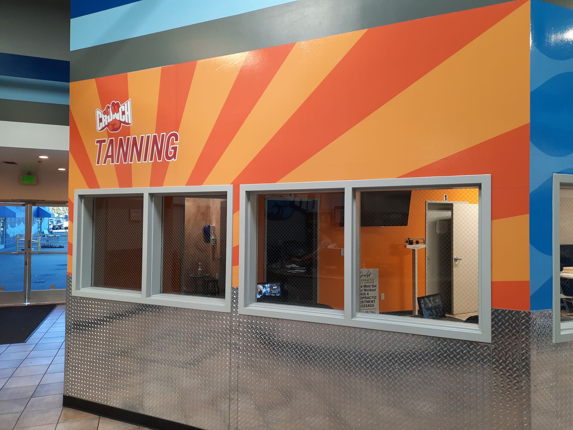 Bright orange storefront with “Training” sign and several windowed service booths in a mall-like interior