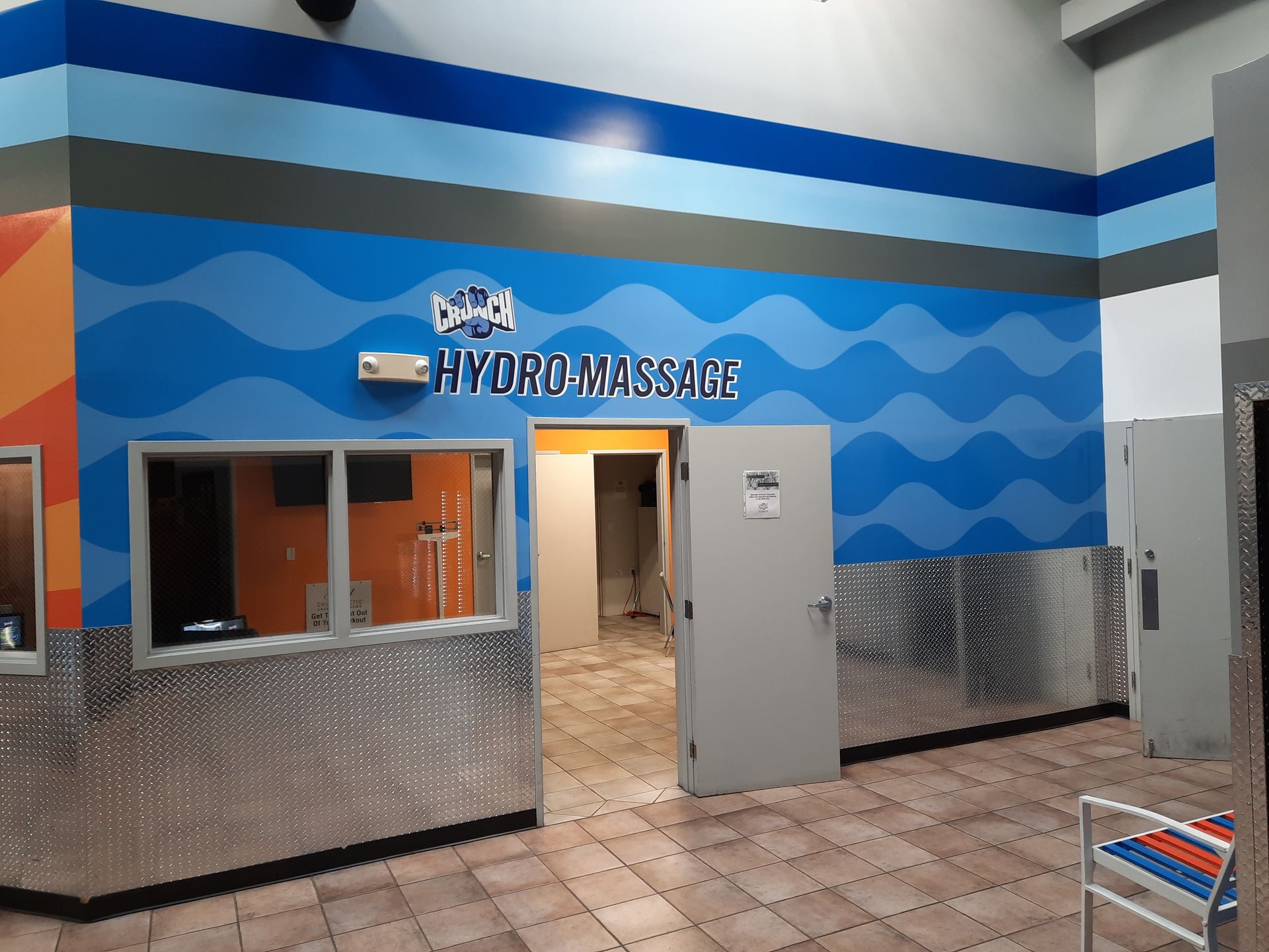 Hydromassage spa entrance with blue wave wall, tiled floor, and open door￼