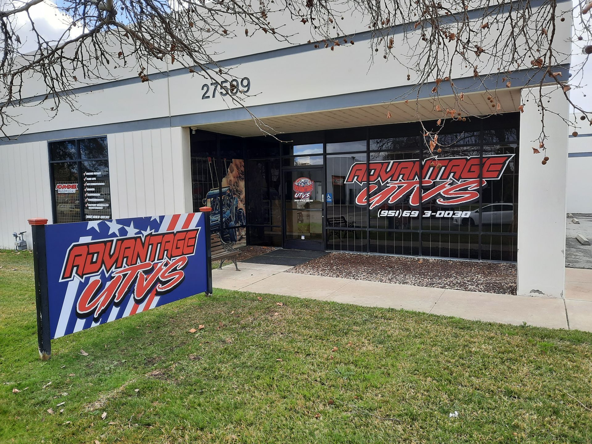 Storefront with “Adventure Labs” signage and a blue A-frame sign on the grass.