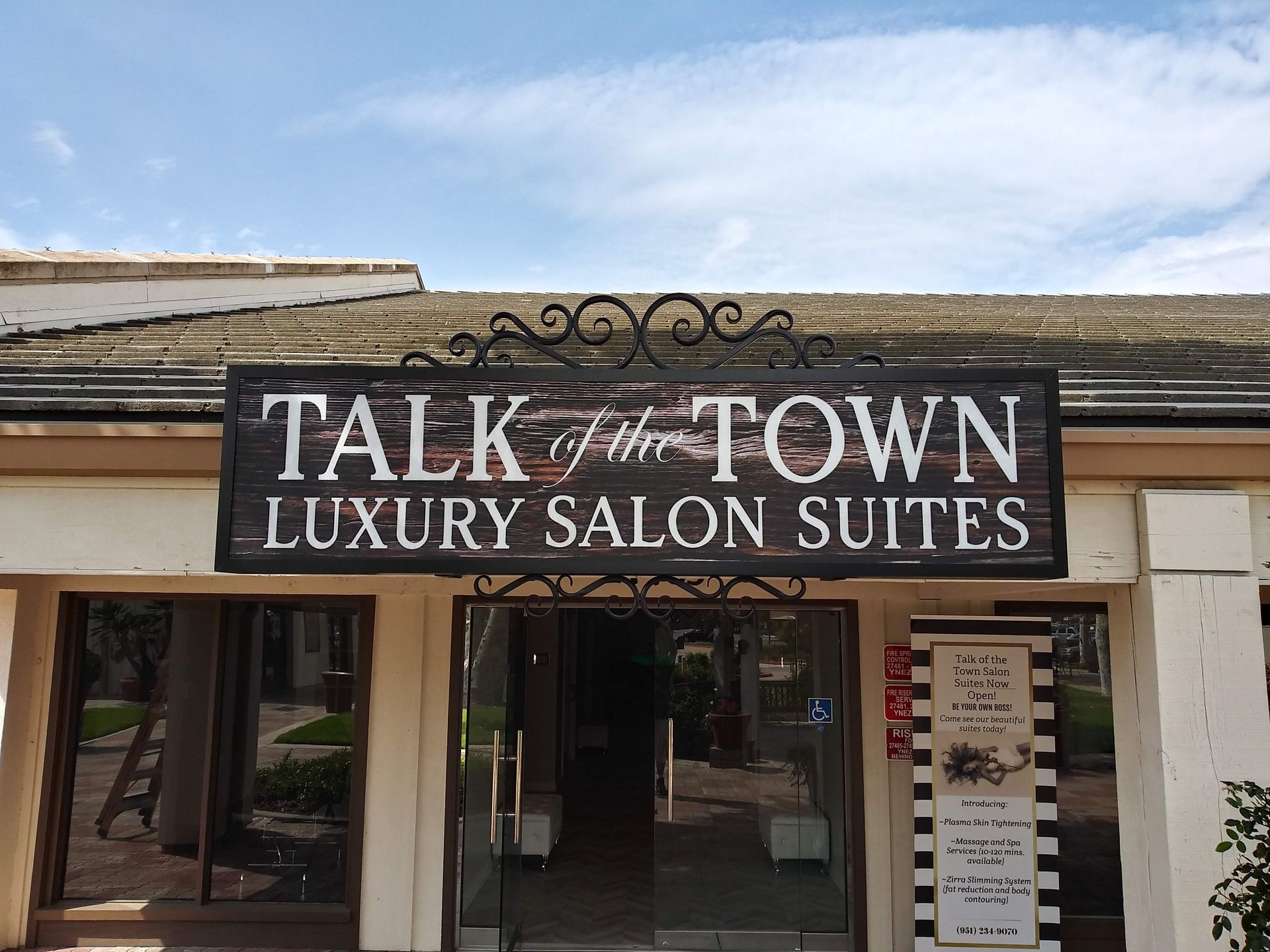 Storefront sign reading “Talk of the Town Luxury Salon Suites” above a salon entrance