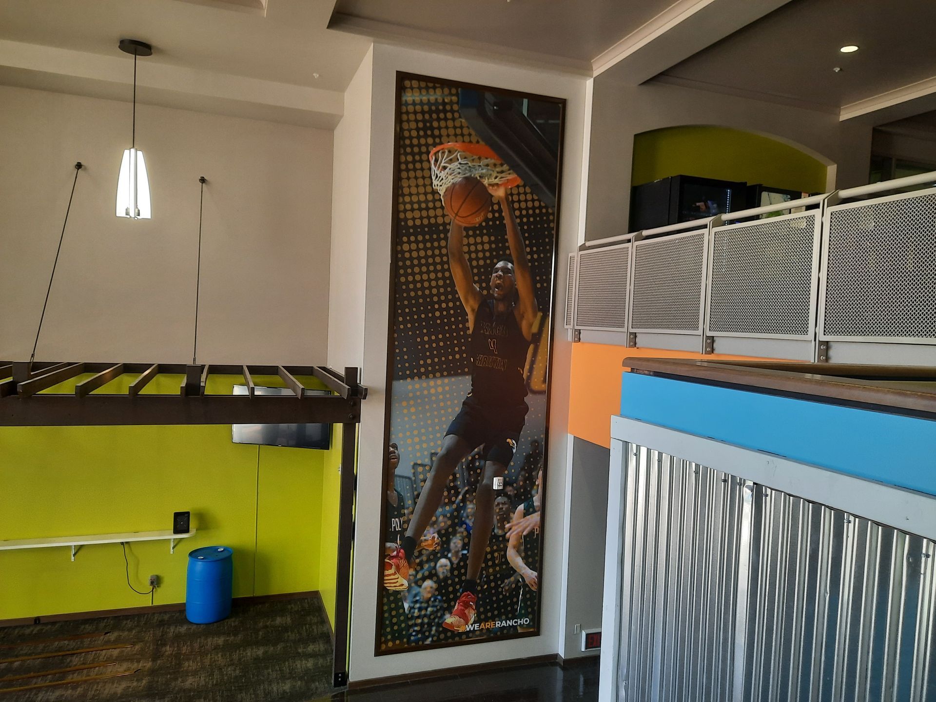 Modern indoor space with colorful counter, hanging lights, and a tall mosaic-style wall panel