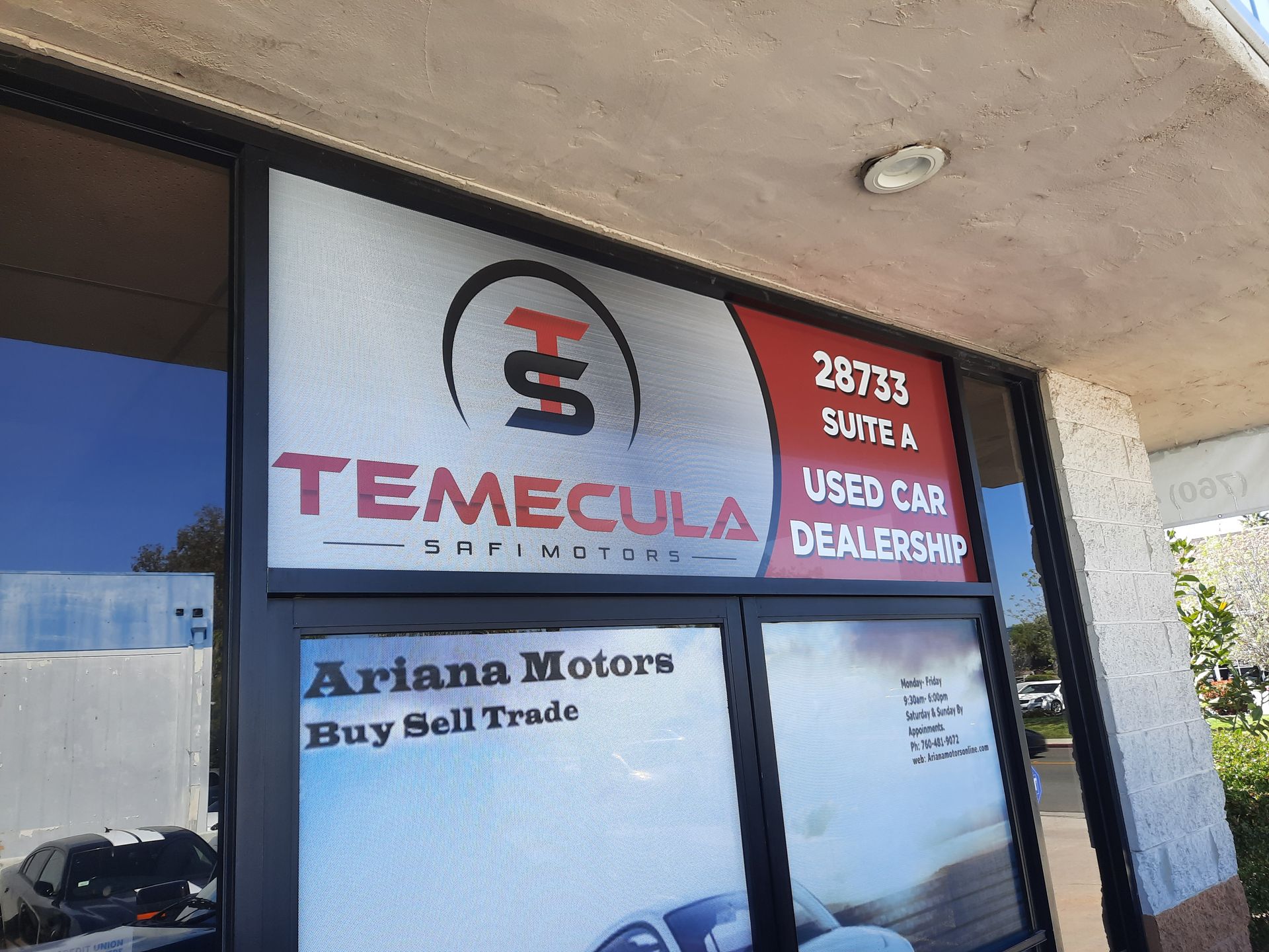 Temecula and Ariana Motors used car dealership signs on a storefront window