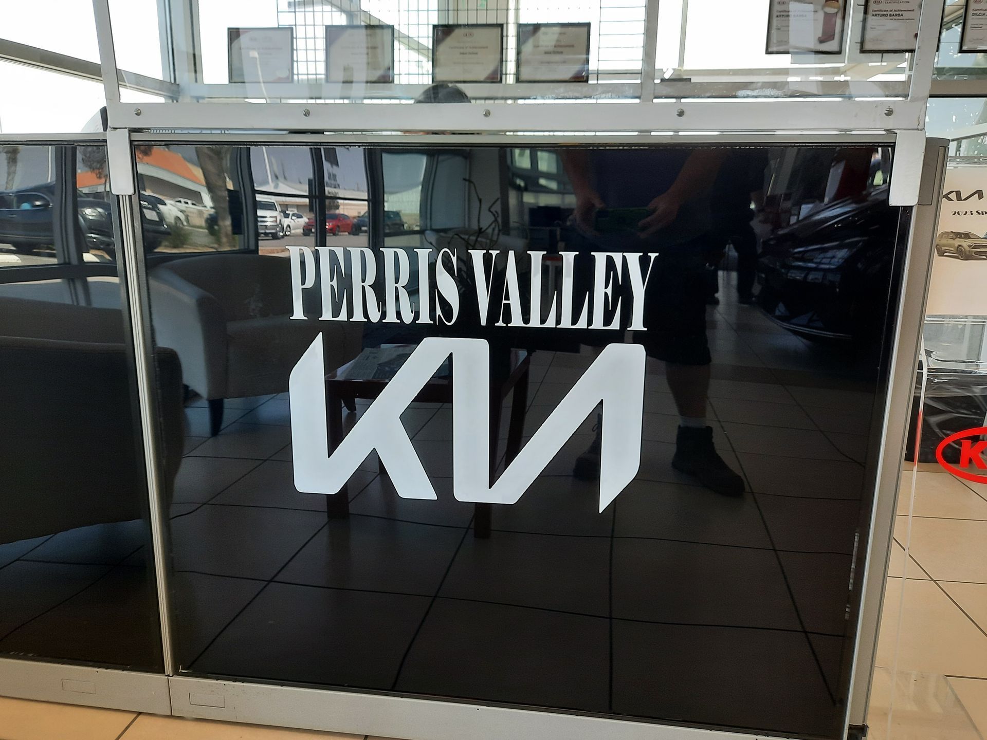 Perris Valley Kia dealership sign on a glossy black wall inside a showroom