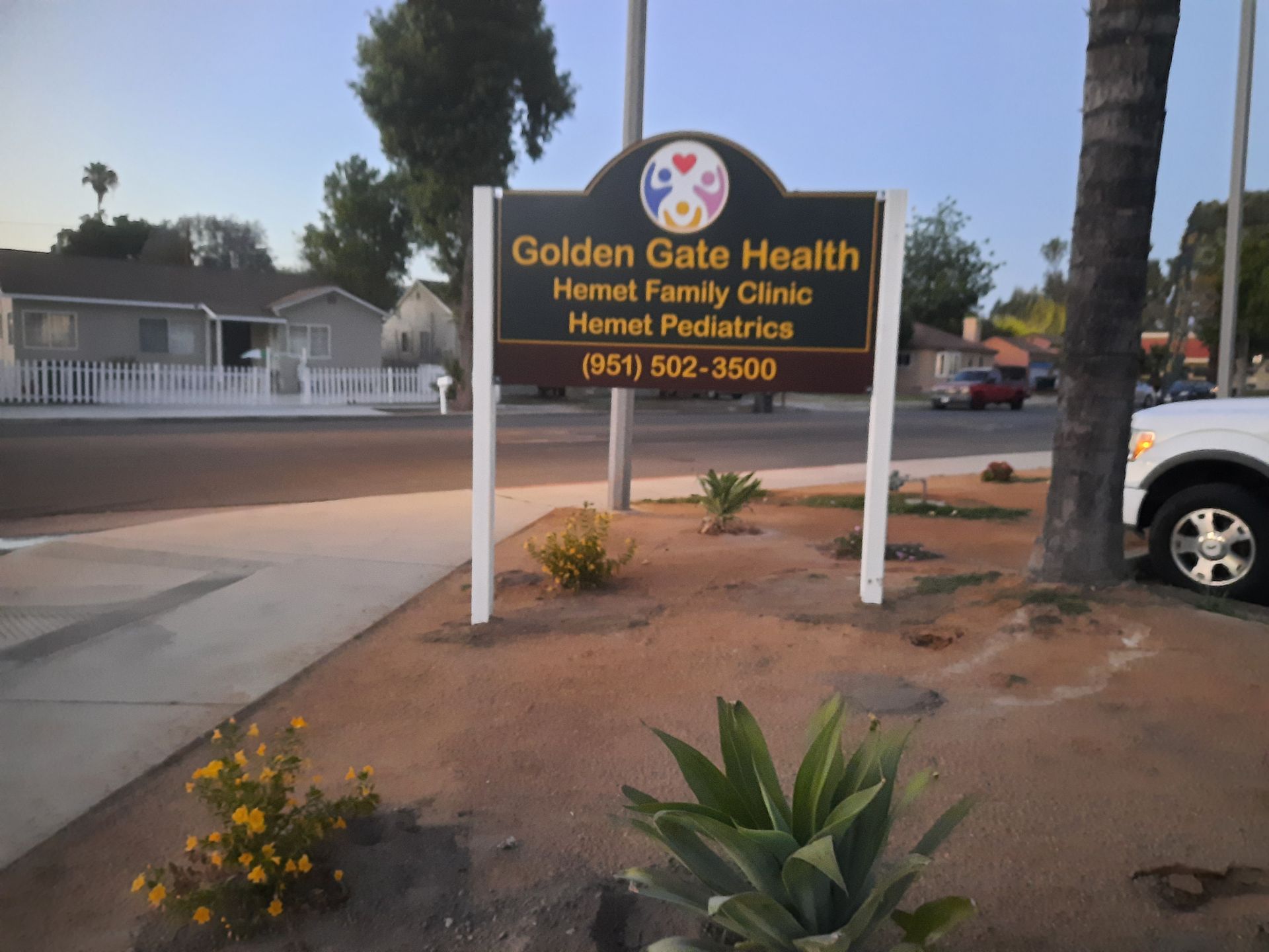 Golden Gate Health Family Clinic sign on a sidewalk beside a road at dusk