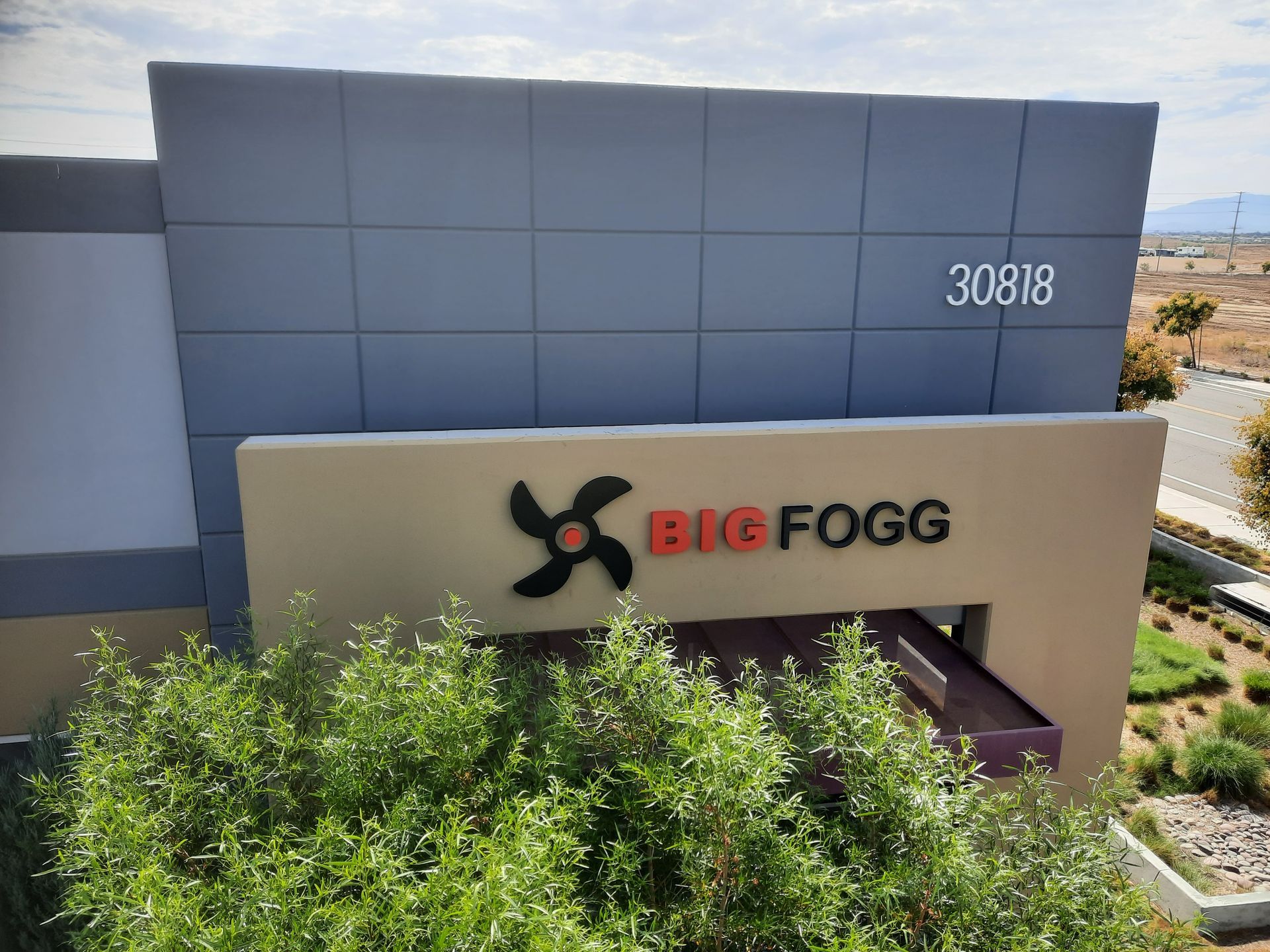 BIGFOGG sign on a beige building with blue wall and desert landscaping