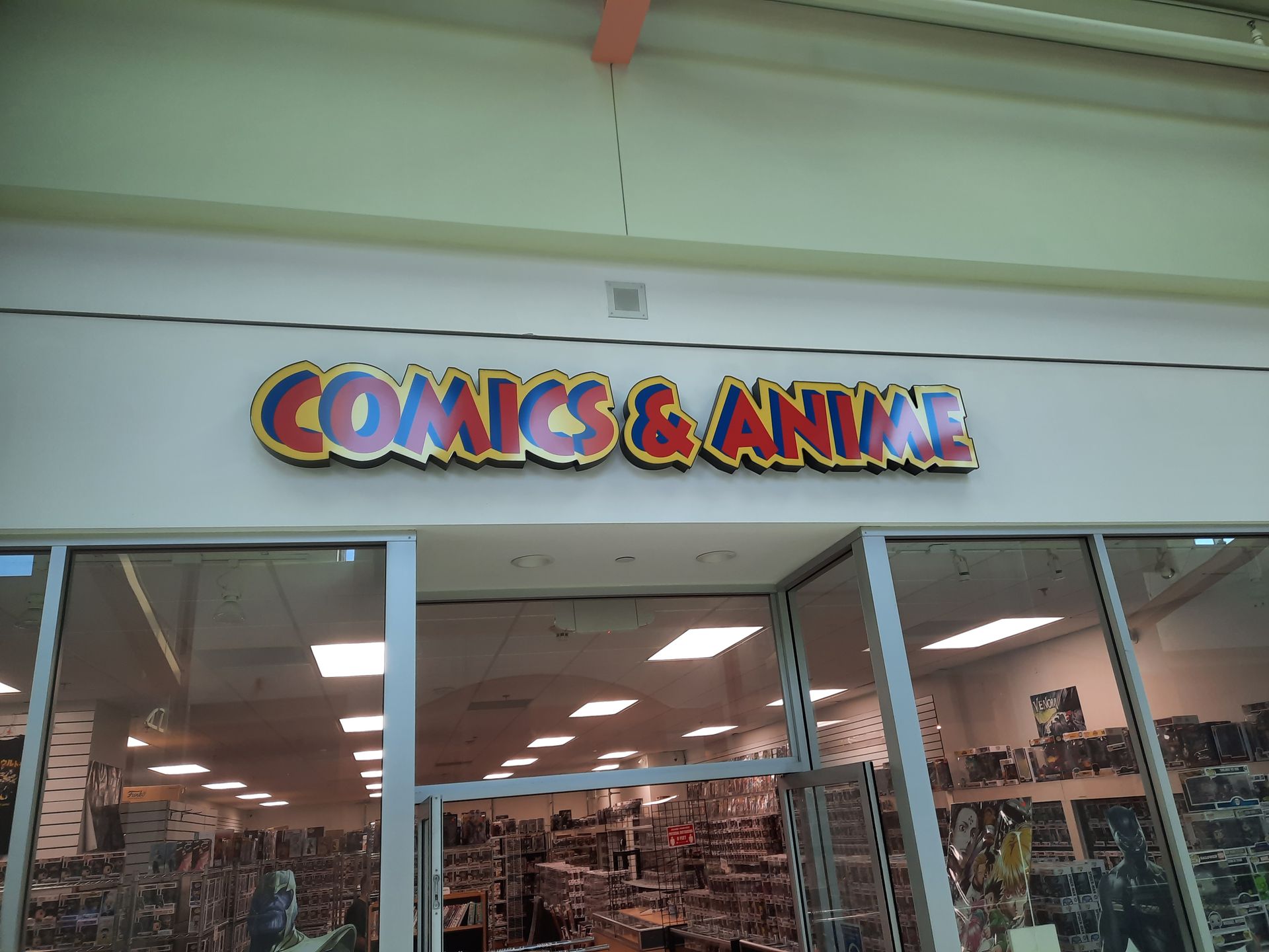 Storefront sign reading “COMICS & ANIME” above a brightly lit shop interior