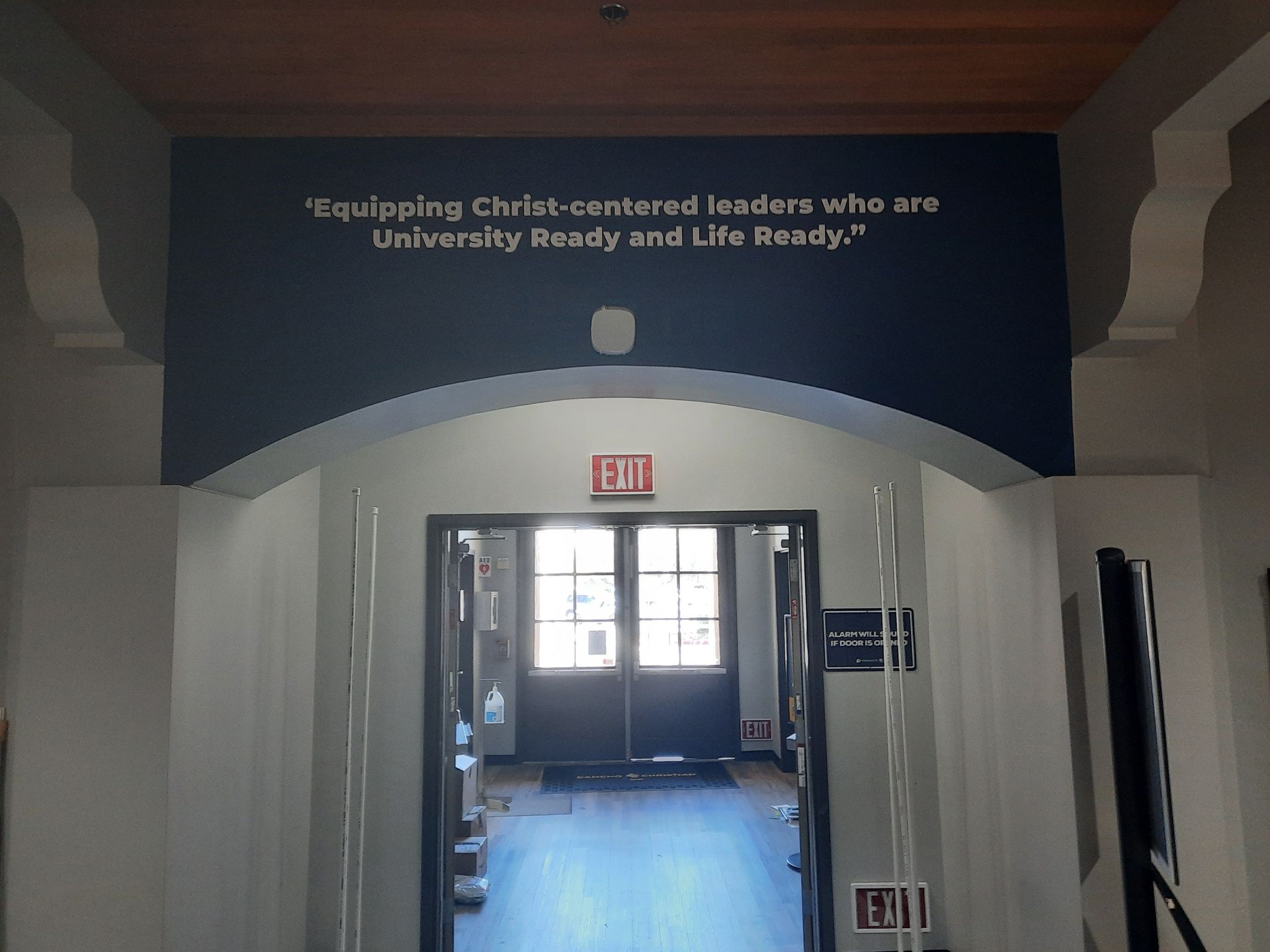 Hallway entrance with blue sign overhead reading “Equipping Christ-centered leaders who are University Ready and Life Ready.”