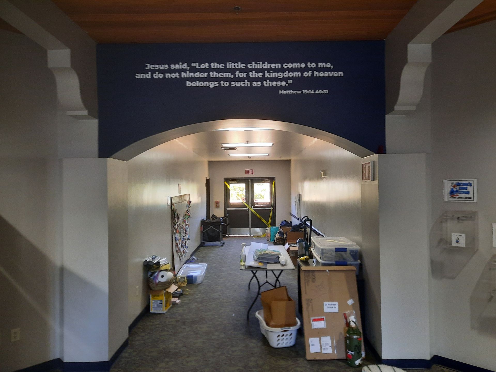 Hospital hallway with a large service cart and boxes under a dark blue wall quote sign