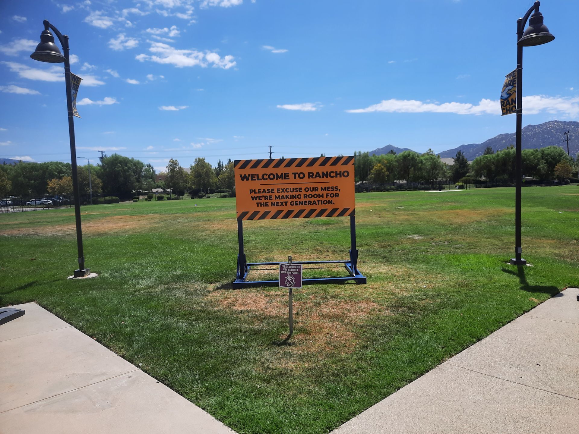 Welcome to Tampico sign in a grassy park with lamp posts and mountains in the distance