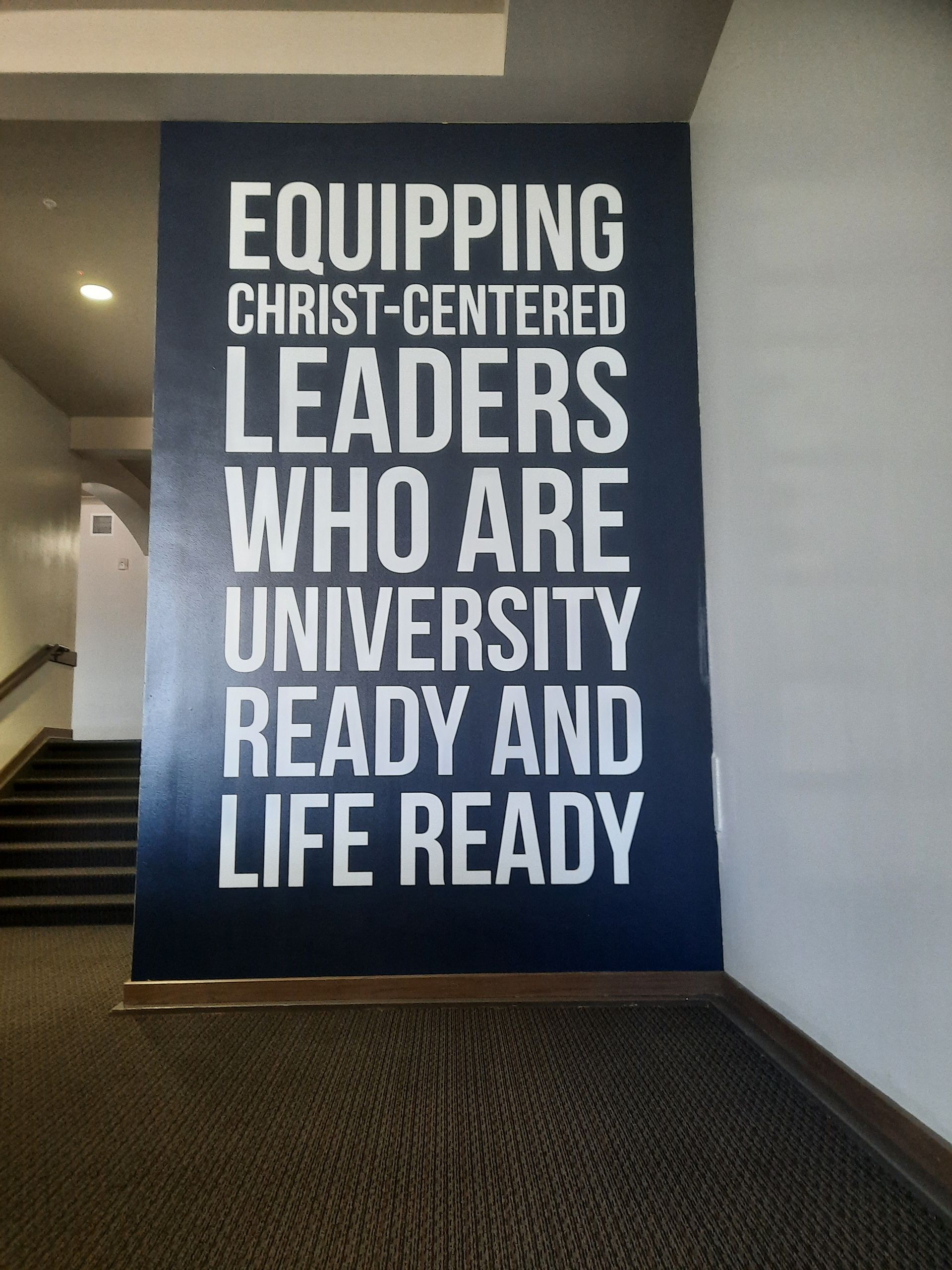 Large wall sign reading “Equipping Christ-centered leaders who are university ready and life ready.”