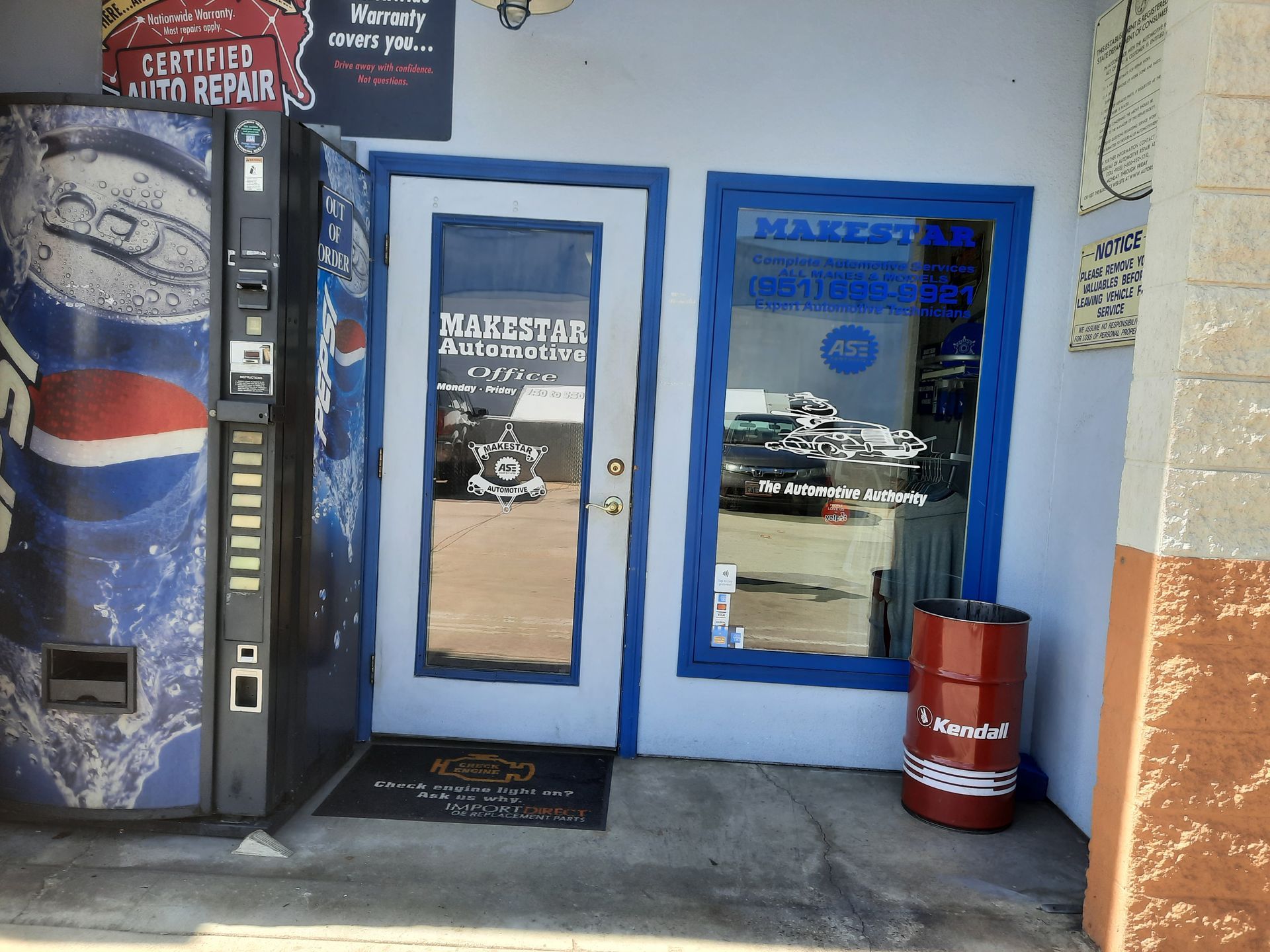 Blue-framed storefront with glass door, Pepsi vending machine, and red canister outside the entrance