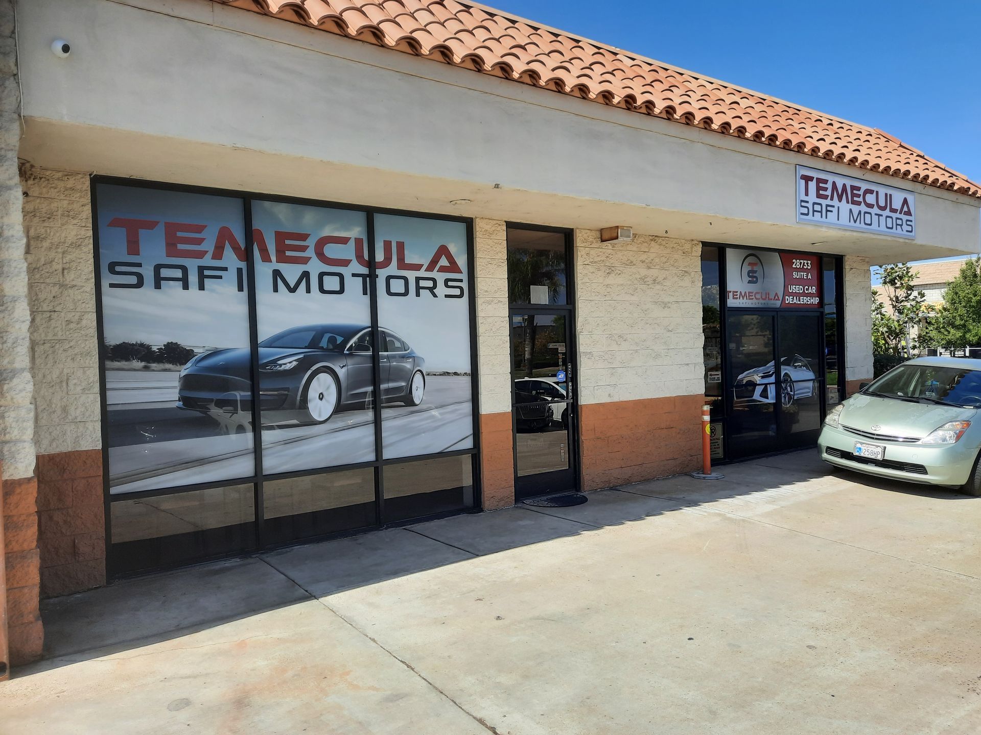 Temecula Safari Motors storefront with glass windows, beige stucco facade, and a parked car outside