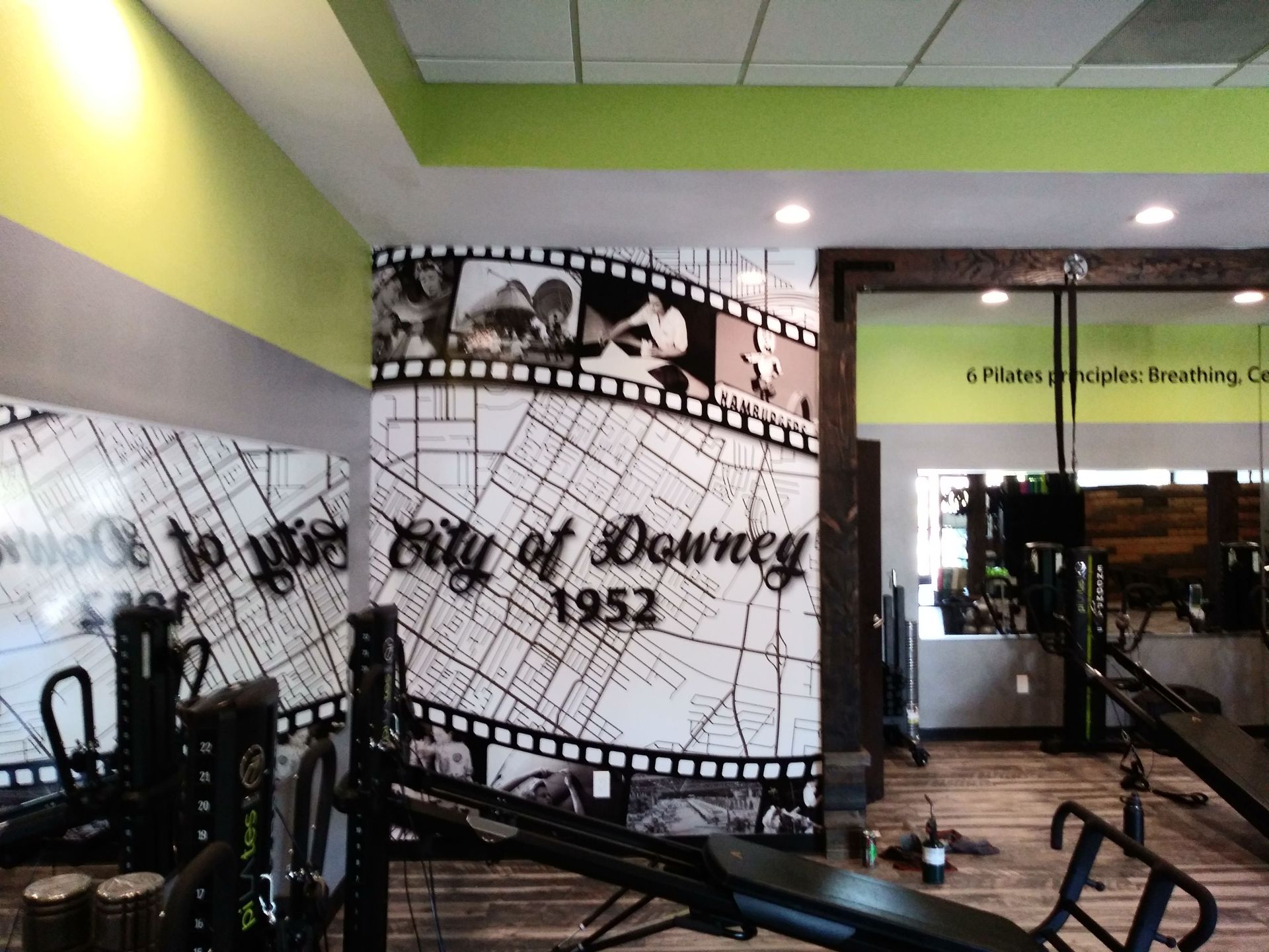 Gym with black exercise bikes and a filmstrip wall mural reading “1952”