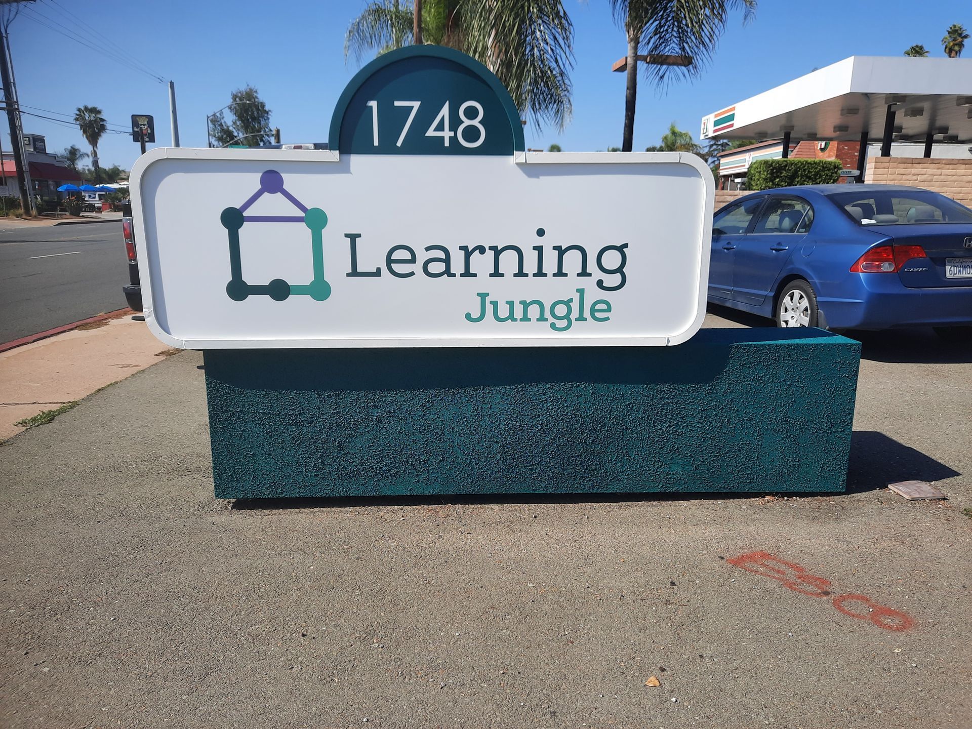 Learning Jungle sign with address 1748 outside on a sunny street corner