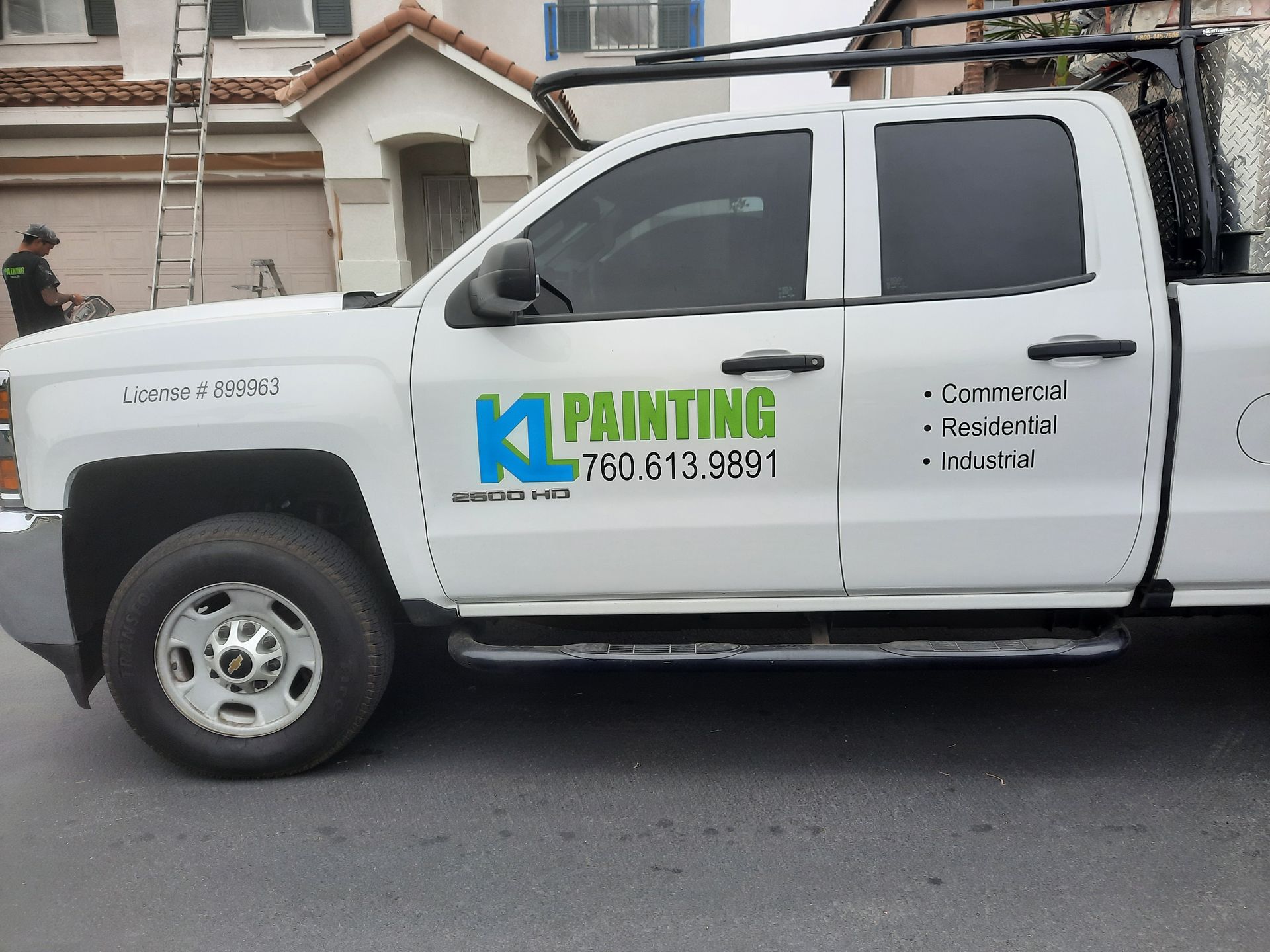White pickup truck with K Painting logo and phone number parked on a residential street