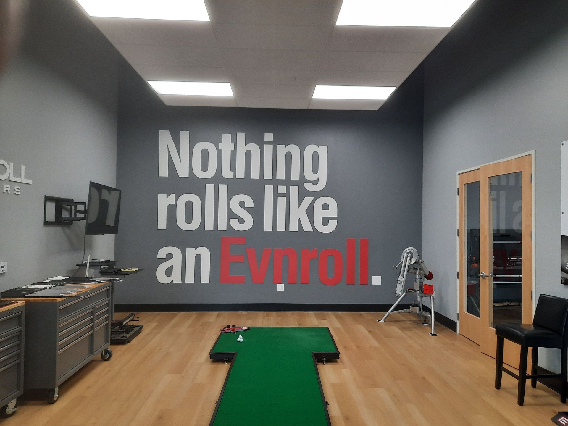 Gym with green turf and wall text: “Nothing rolls like an Evroll.”