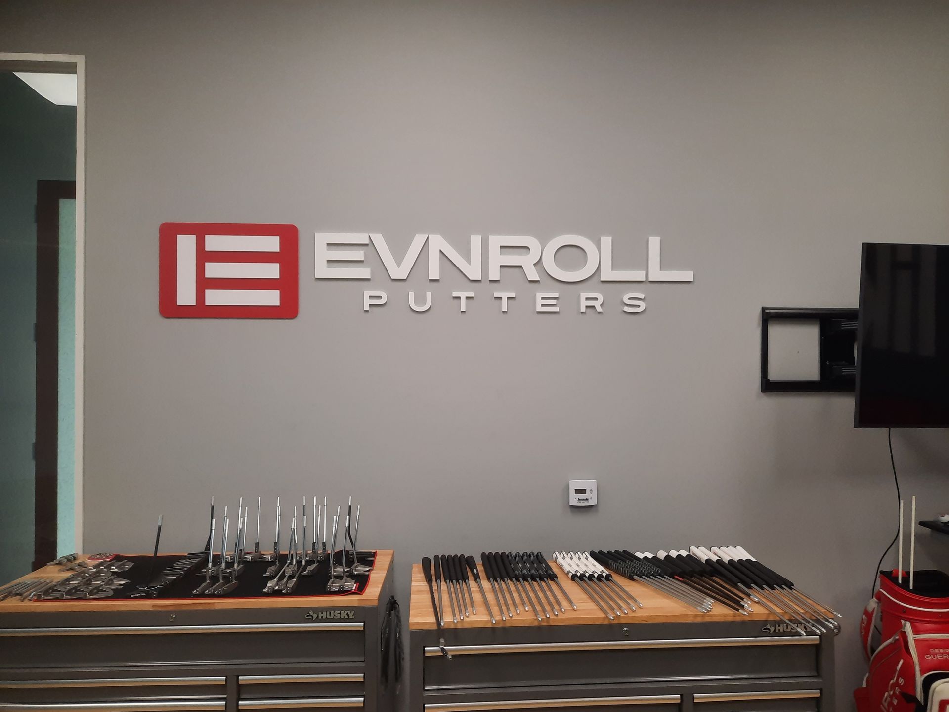 EVNROLL Putters showroom wall with display tables of golf putters and accessories