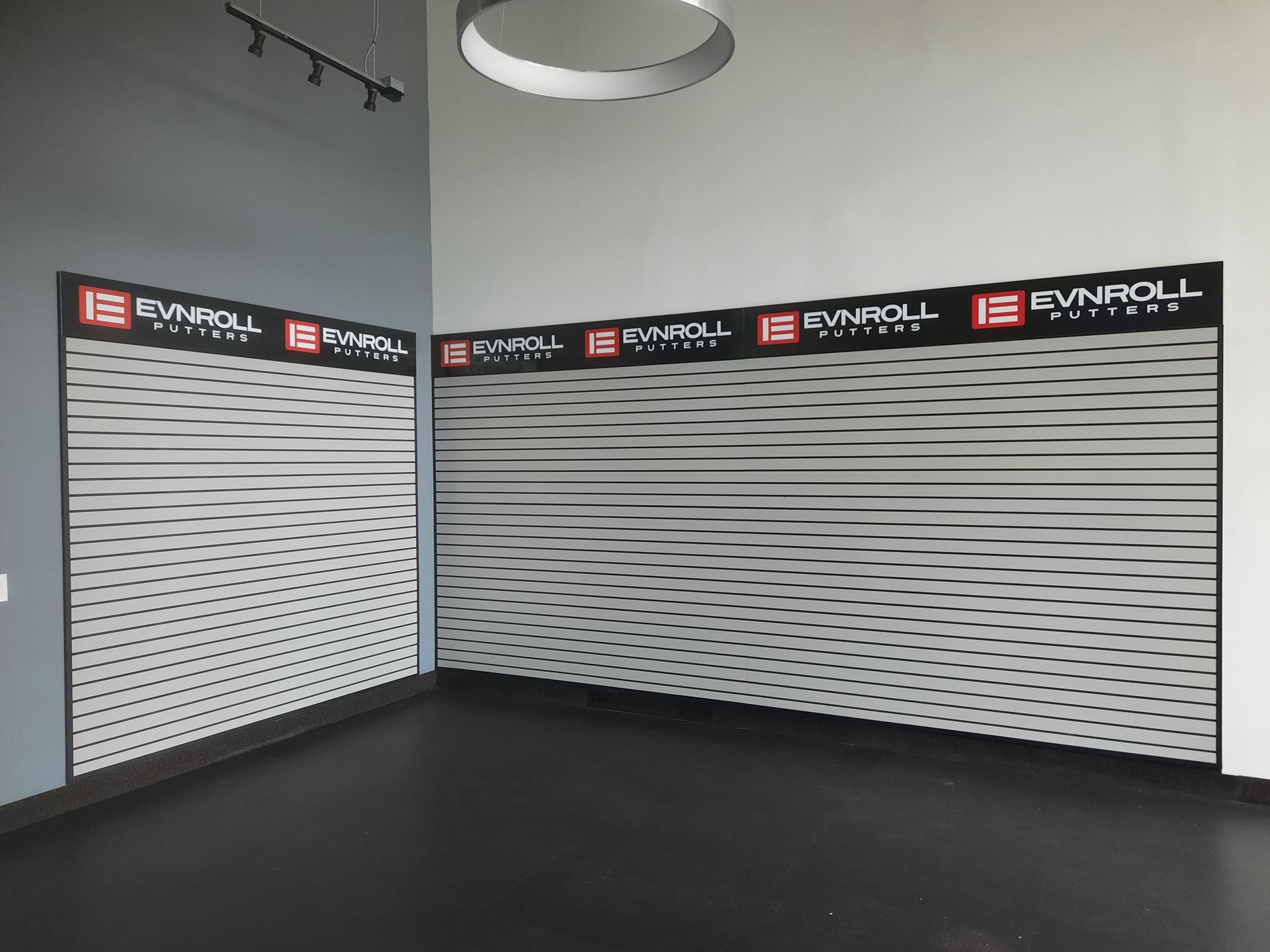 Empty retail showroom with black floor and white slatwall display panels along two walls