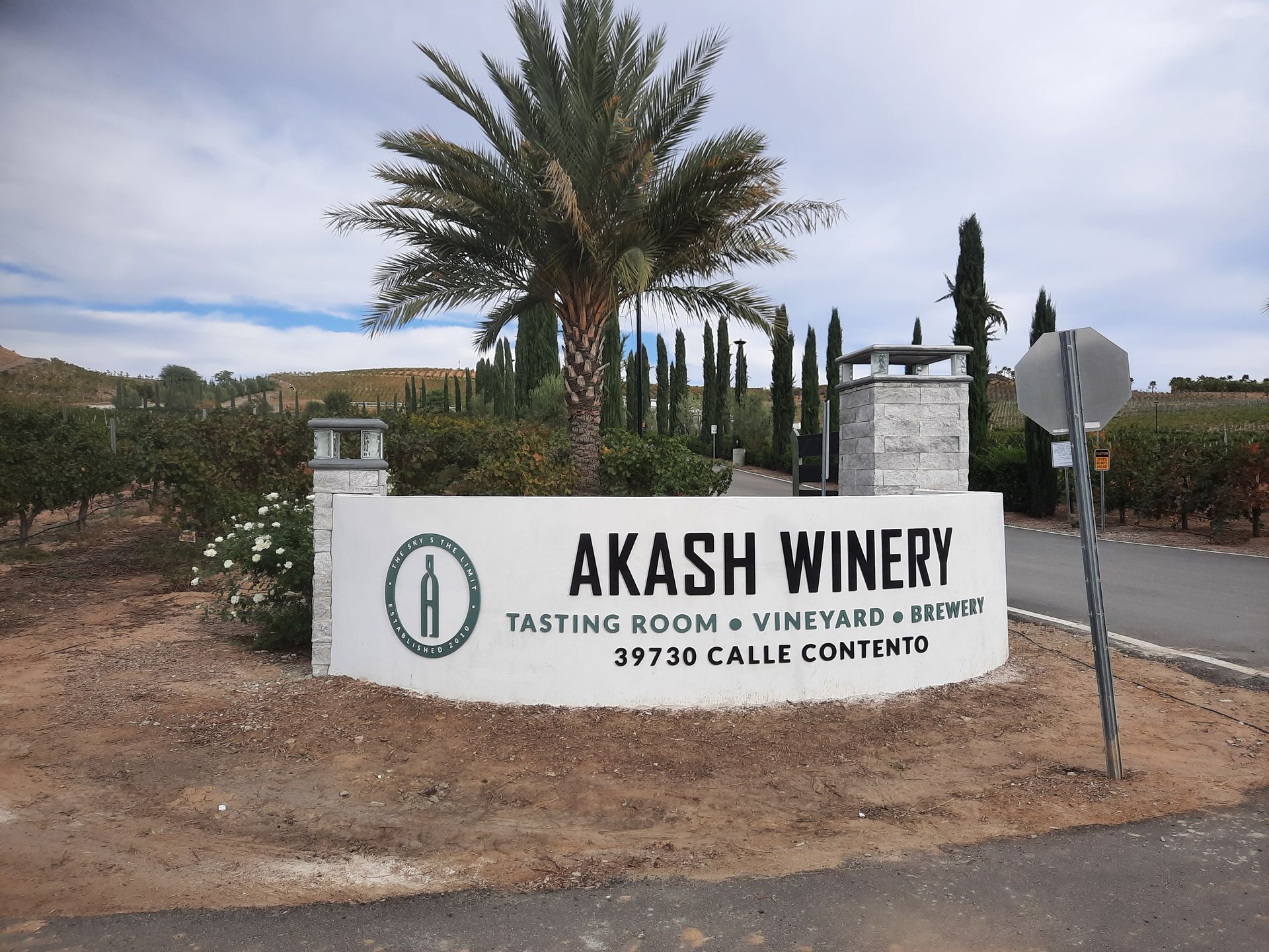 Akash Winery sign in front of palm trees and desert landscaping